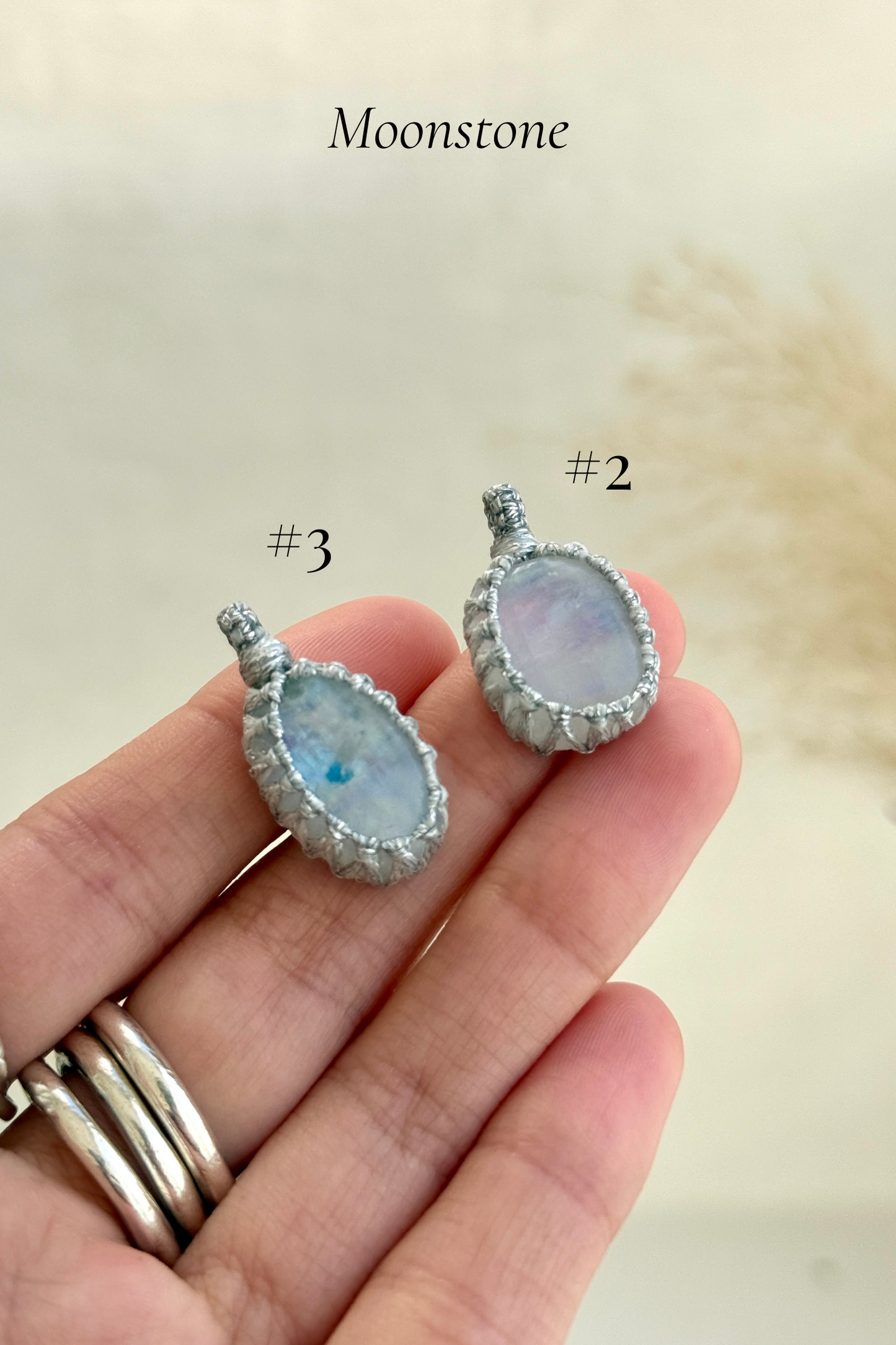 Close-up of Candy Charms featuring Moonstone pendants held in hand, showing the size of the charm and detailed gemstone features.
