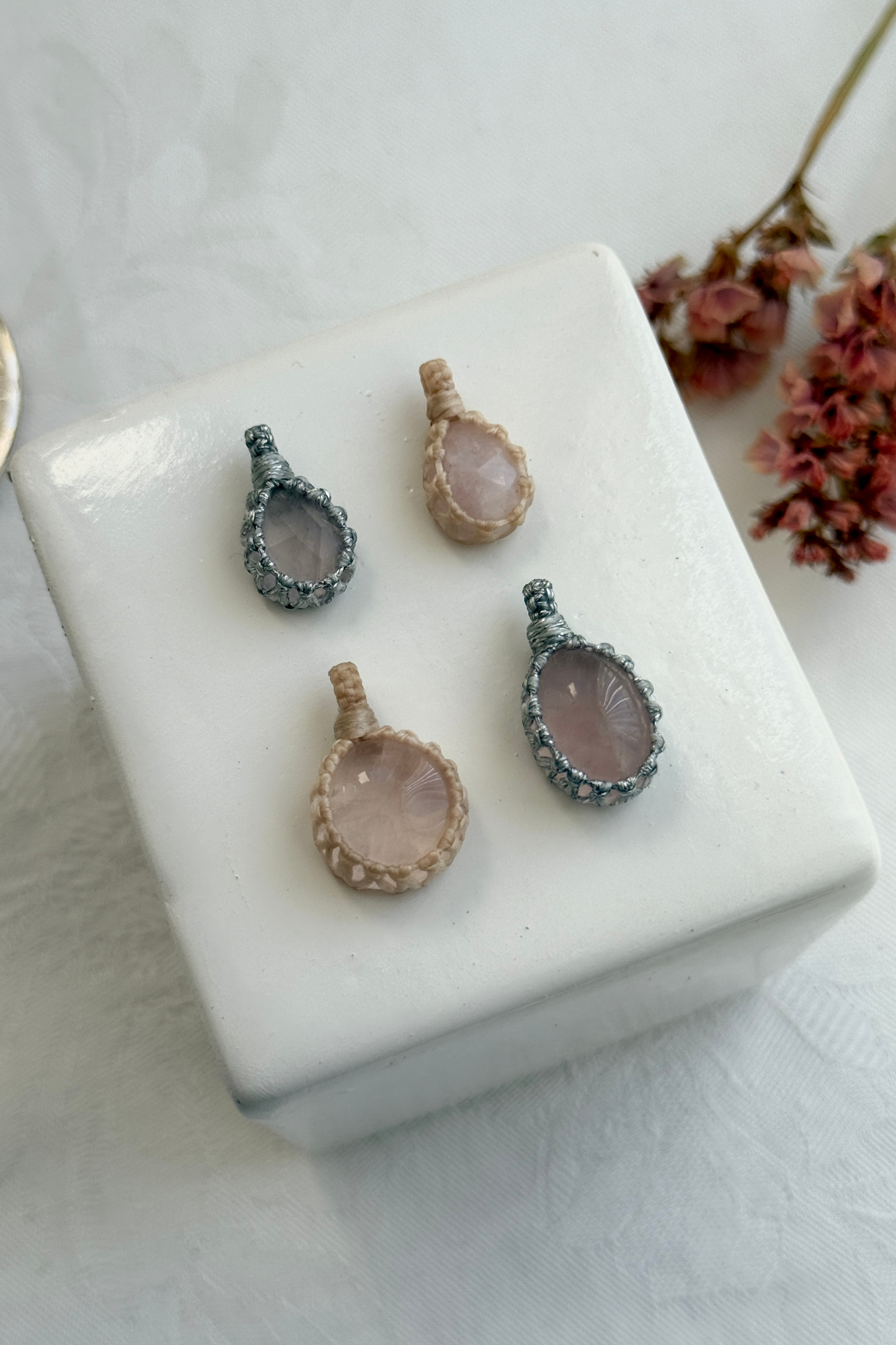 Close-up view of handmade Candy Charms with natural Rose Quartz gemstone pendants, showcasing the macrame wrapping and unique stone details.