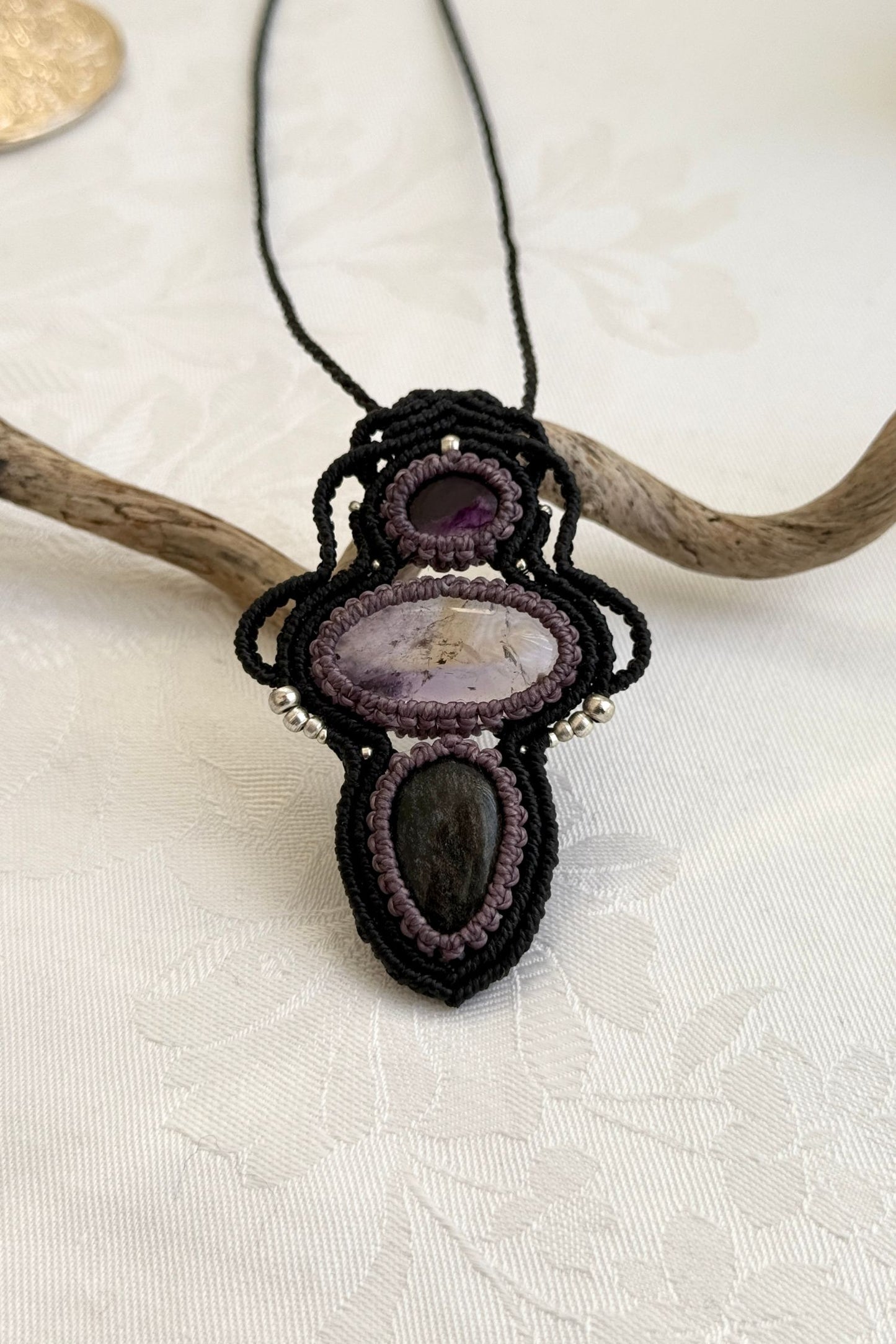 Close-up of the Amethyst, Ametrine and Silver Sheen Obsidian macrame necklace in a unique setting. Highlighting the craftsmanship and gemstone details.