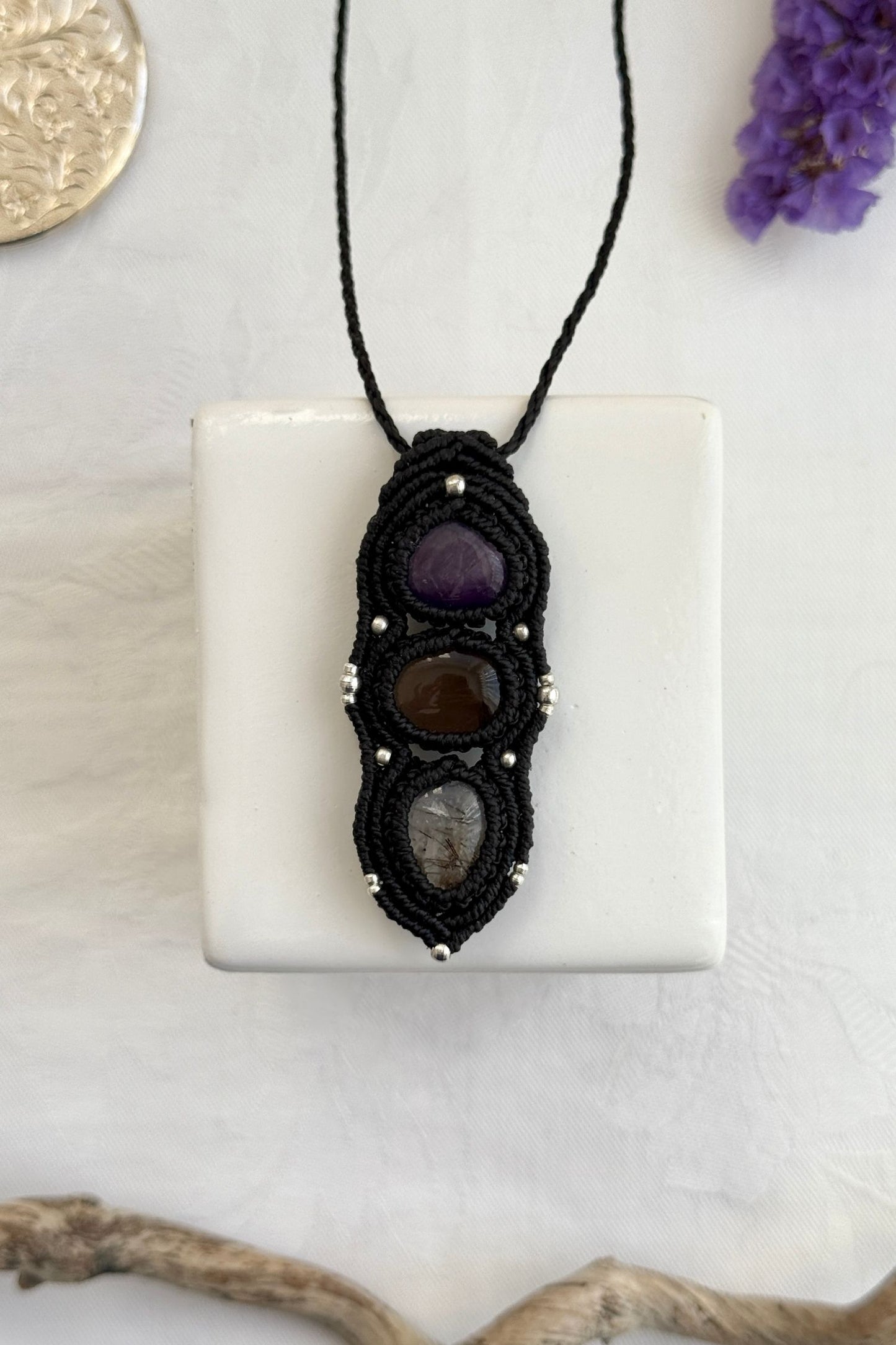 Handmade macrame necklace with Amethyst, Smoky Quartz and Tourmaline Quartz gemstones, part of the Nocturnal Collection. One-of-a-kind design, laid flat for an artistic display.