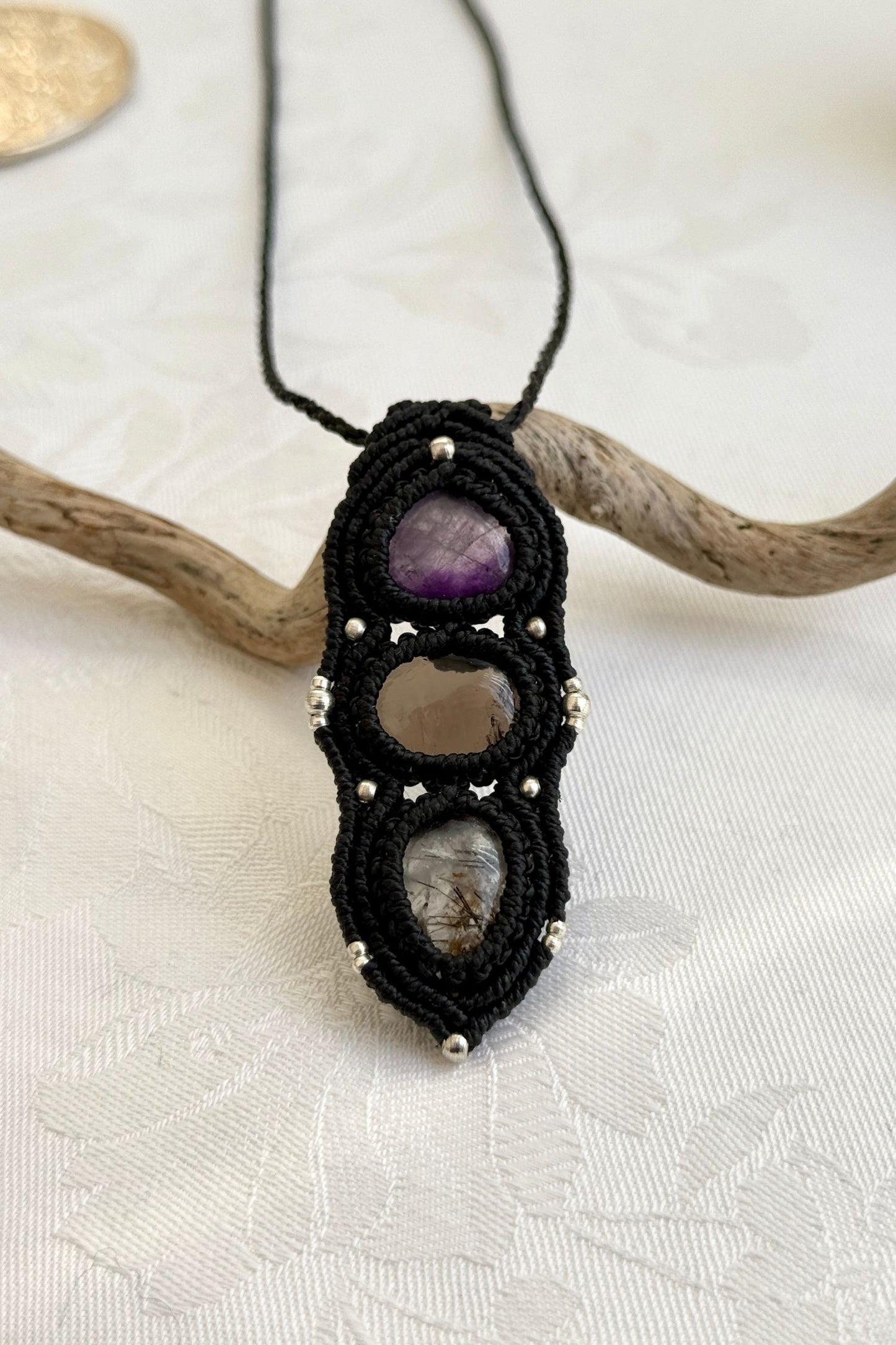 Close-up of the Amethyst, Smoky Quartz and Tourmaline Quartz macrame necklace in a unique setting. Highlighting the craftsmanship and gemstone details.