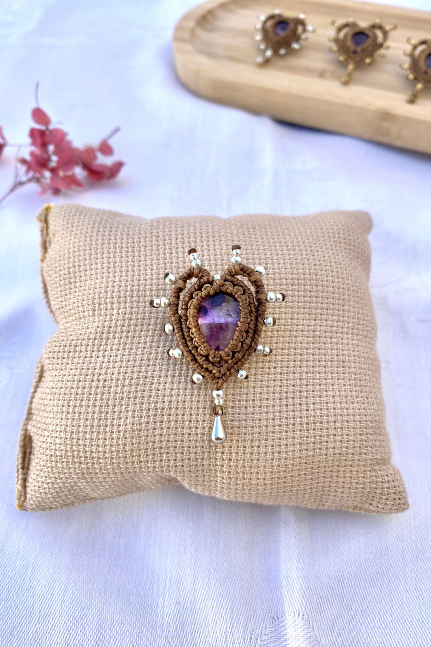 Detailed view of a single handmade Cupid Amethyst Brooch, featuring an amethyst gemstone, heart-shaped macrame, and an elegant drop bead accent.