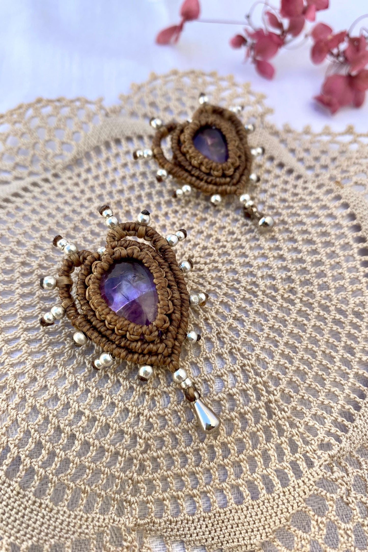 Close-up of the Cupid Amethyst Brooches with silver accents, showcasing the intricate macrame knots and shimmering amethyst gemstones.