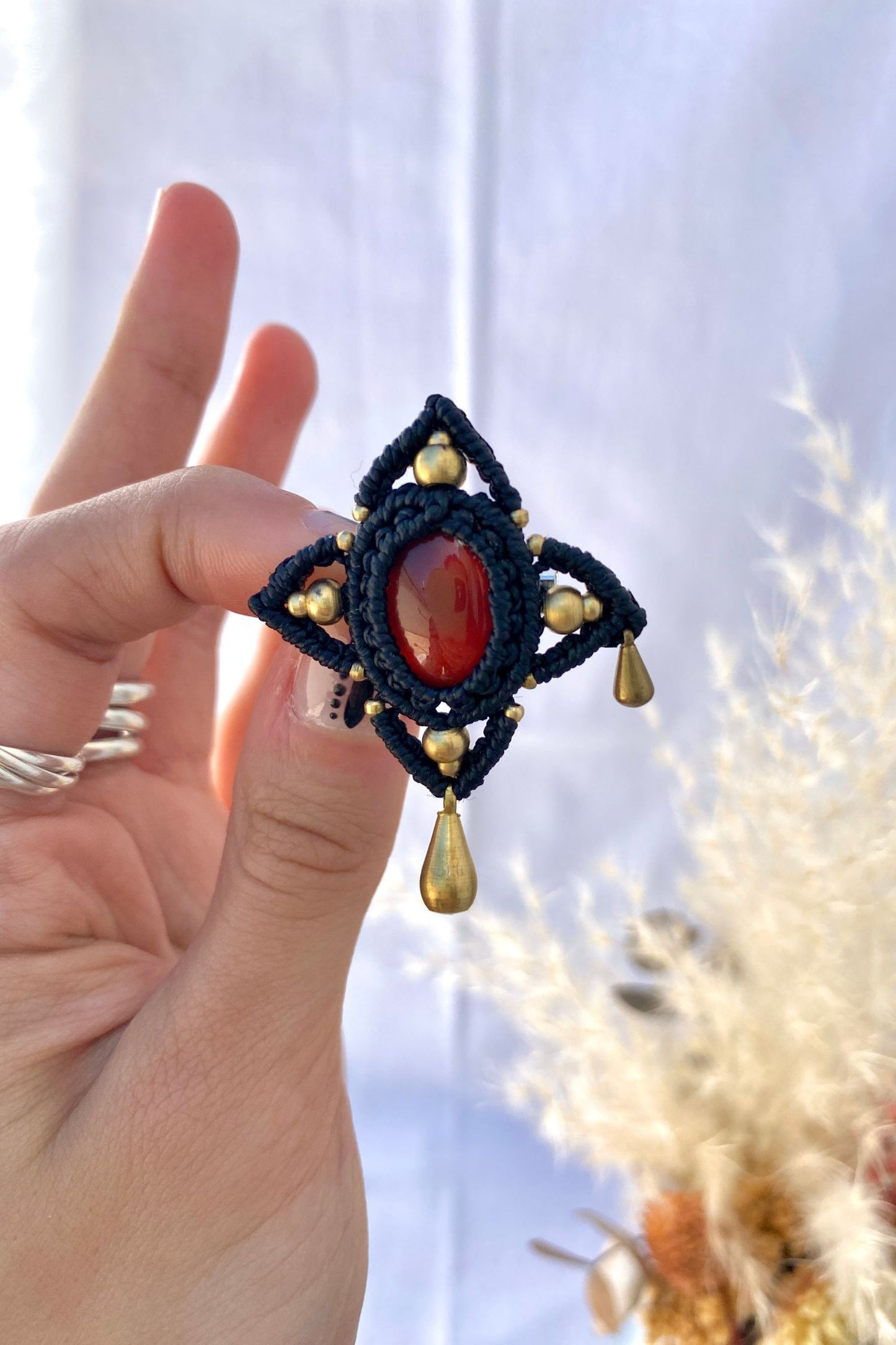 Handmade gothic statement brooch featuring a bold red Carnelian gemstone at the center, with asymmetrical golden drops. A striking accessory that adds a touch of elegance and mystery.