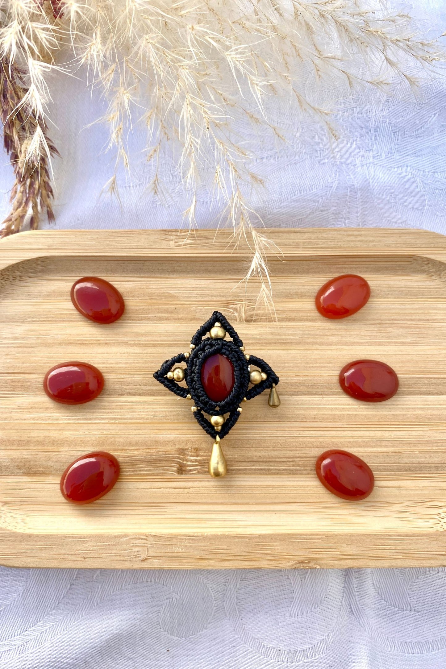 Handmade gothic brooch with a vibrant red Carnelian stone, displayed flat to highlight its intricate asymmetrical golden drop details and bold design.