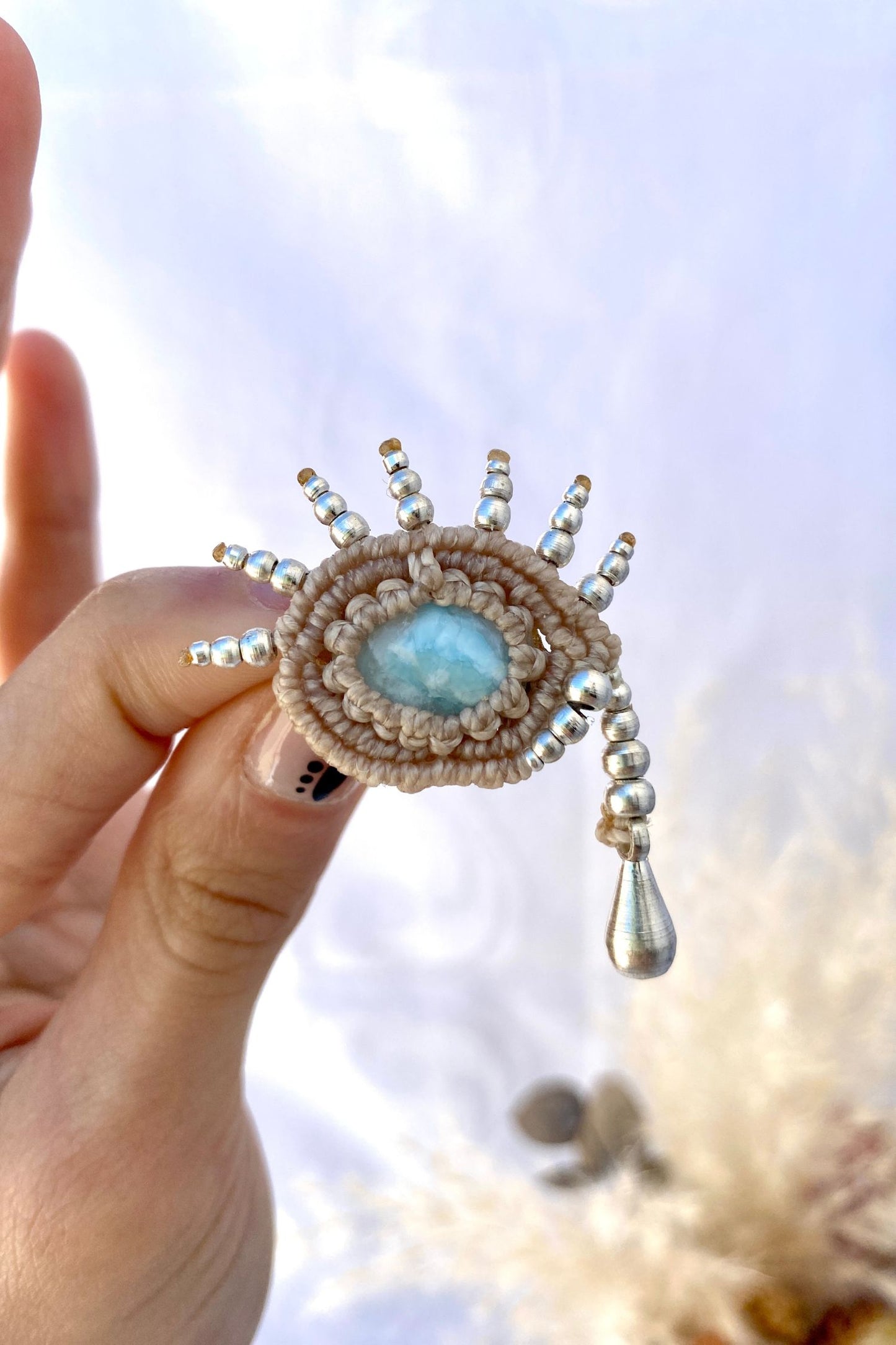 Handmade Larimar brooch securely held in hand, showing its size and fine silver bead craftsmanship.