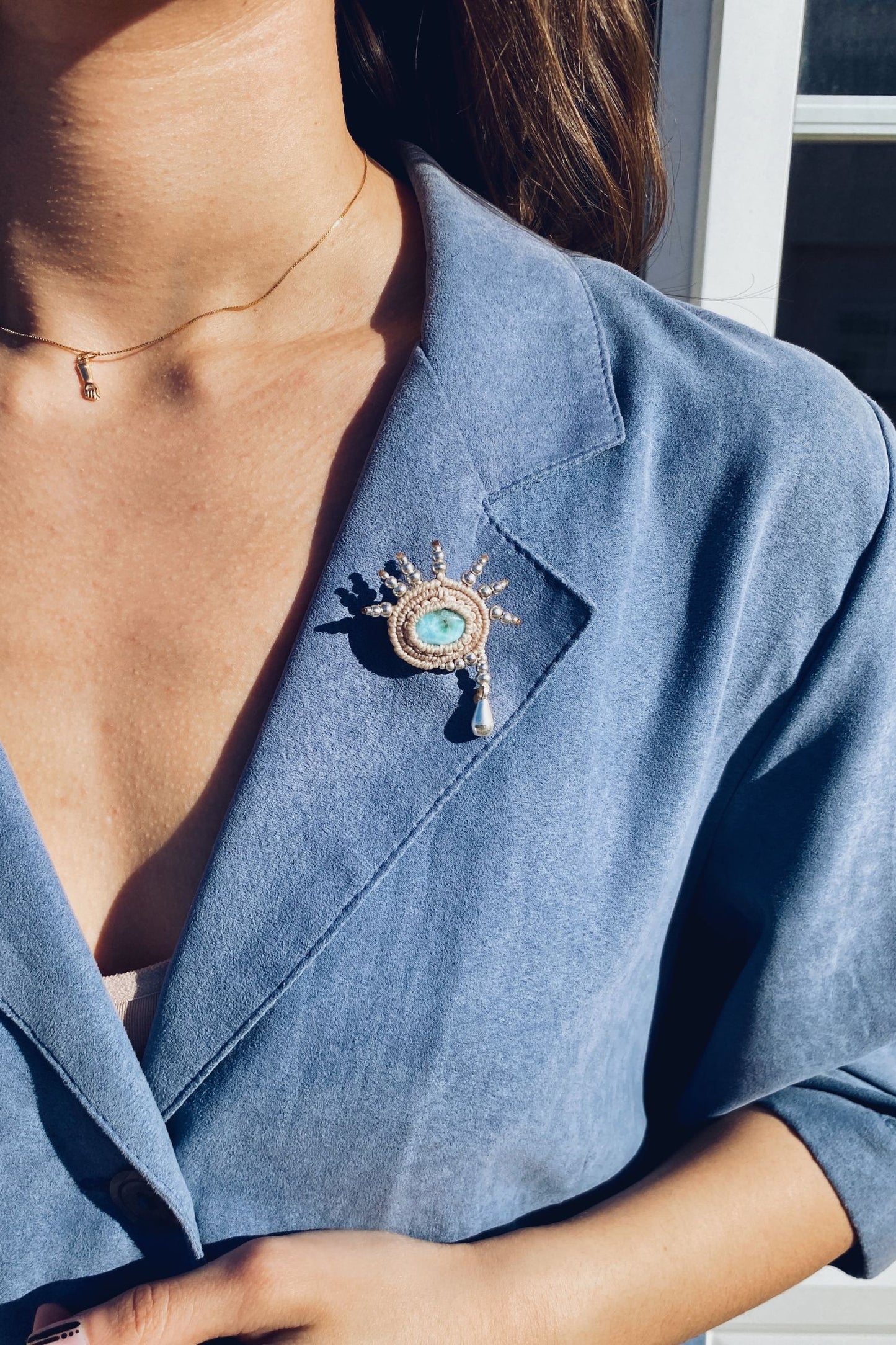 Handmade Larimar brooch with delicate silver beadwork, styled on a blue blazer for a cohesive and sophisticated look.