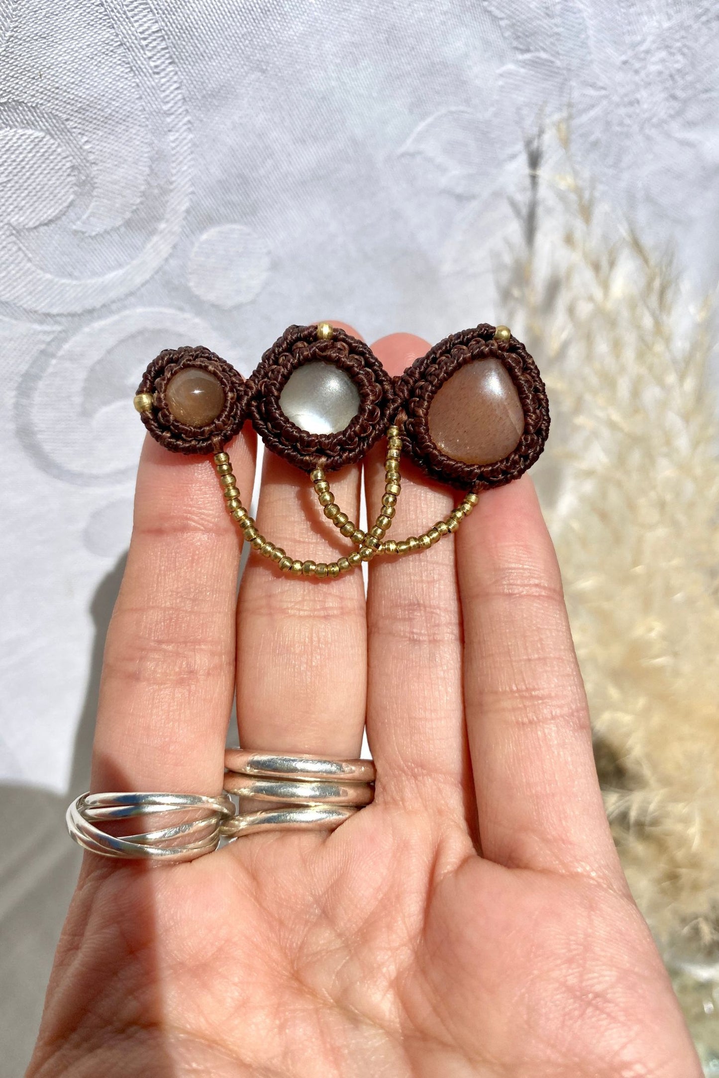 Handmade statement brooch held in hand, giving a sense of its size and the detailed craftsmanship of the Peach Moonstone gemstones.