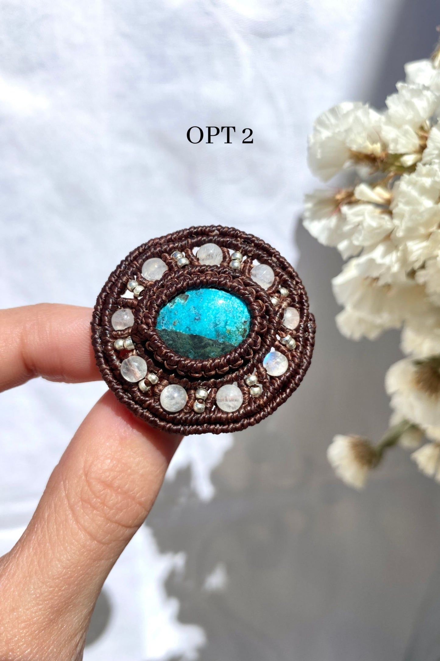 Handmade statement brooch with a round turquoise gemstone and moonstone bead details, held in hand to highlight its size and craftsmanship.