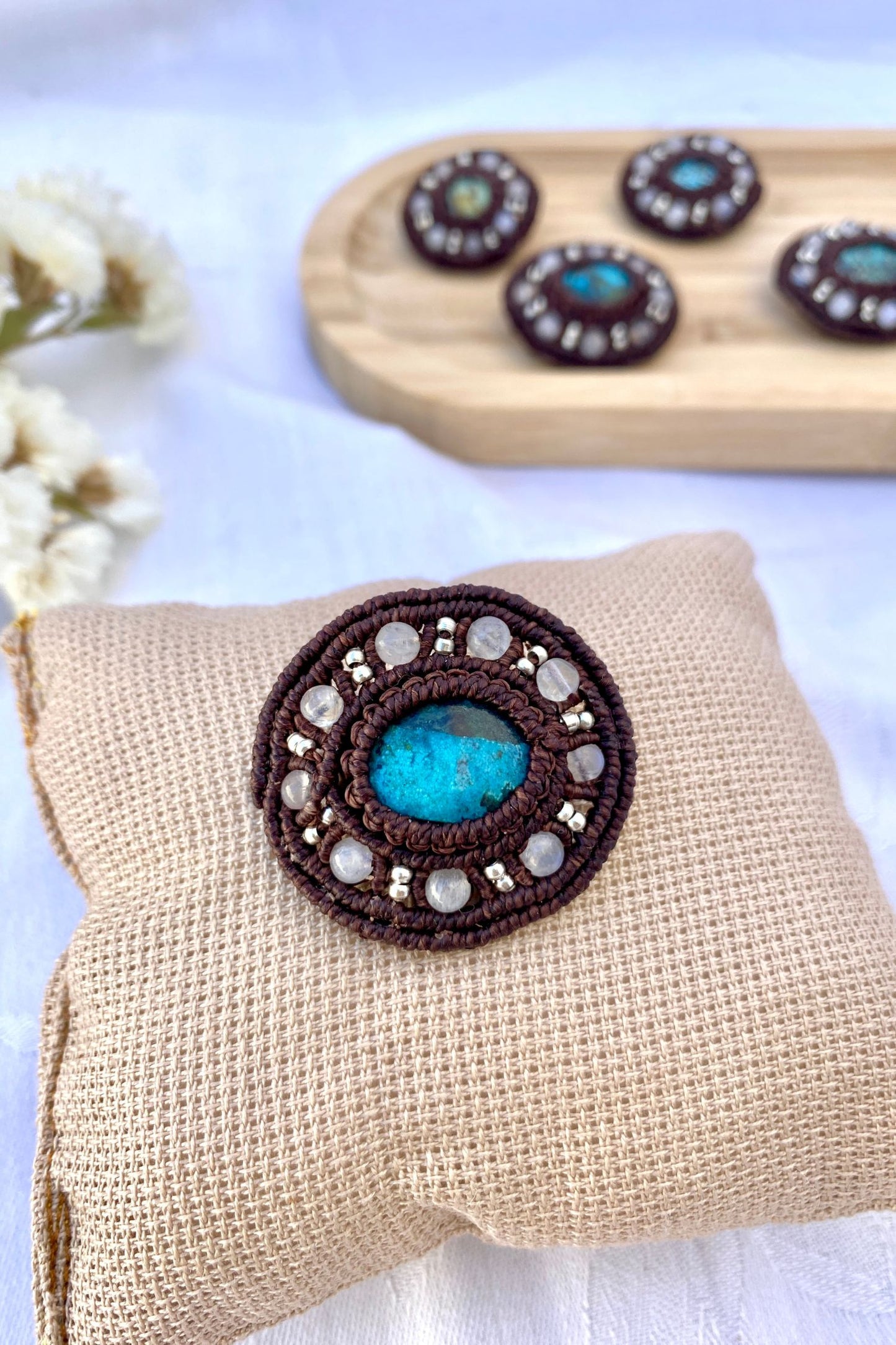 Close-up of the handmade turquoise brooch, showcasing the intricate macrame craftsmanship, natural stone variations, and delicate moonstone accents.