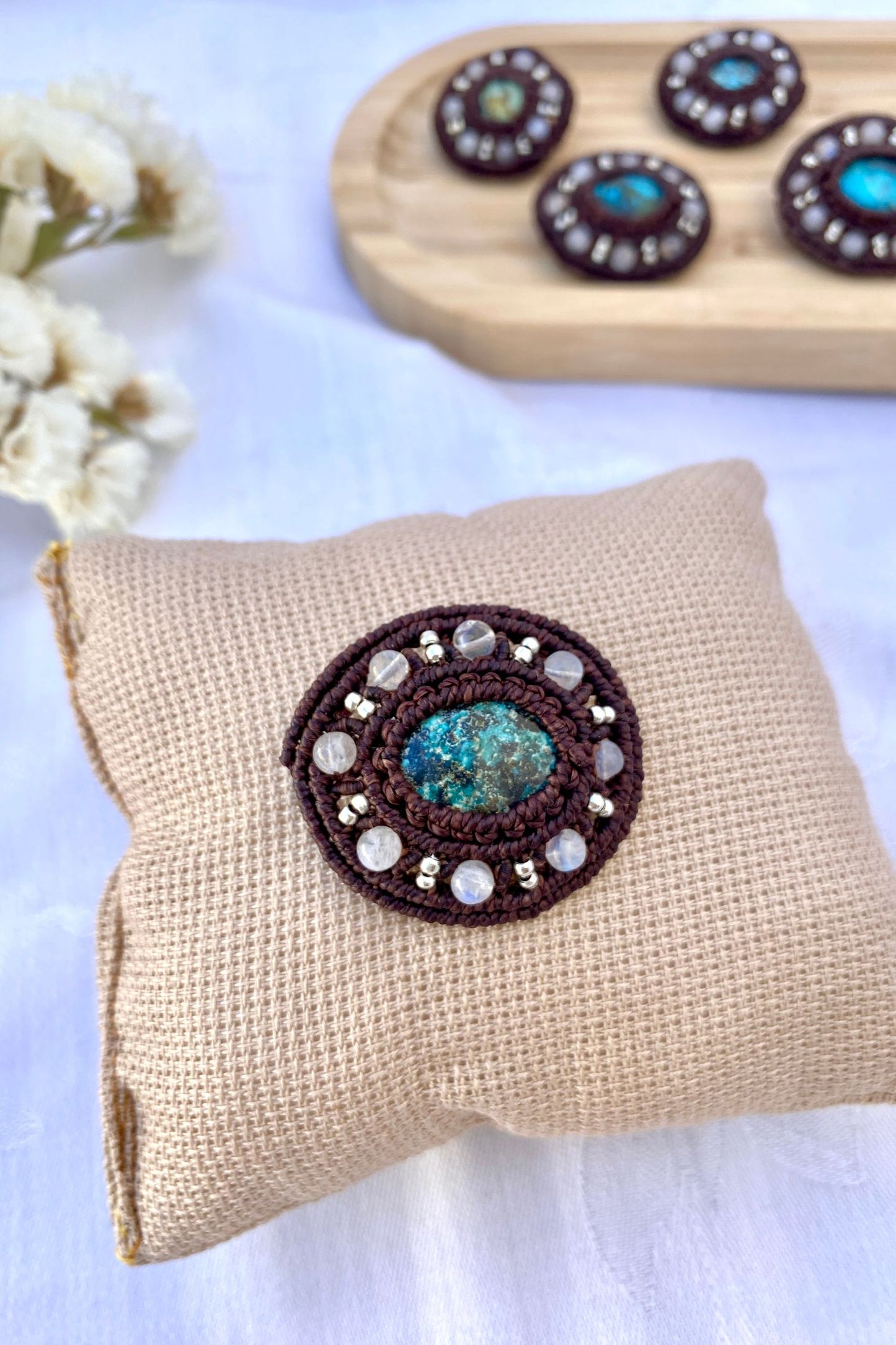 Detailed view of the round turquoise gemstone and moonstone beadwork in this handmade boho-inspired brooch.