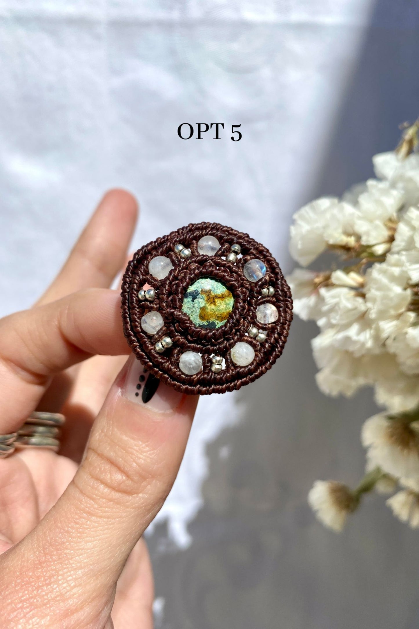 Handmade turquoise brooch with a round design, held in hand to showcase its size, shape, and natural stone details.