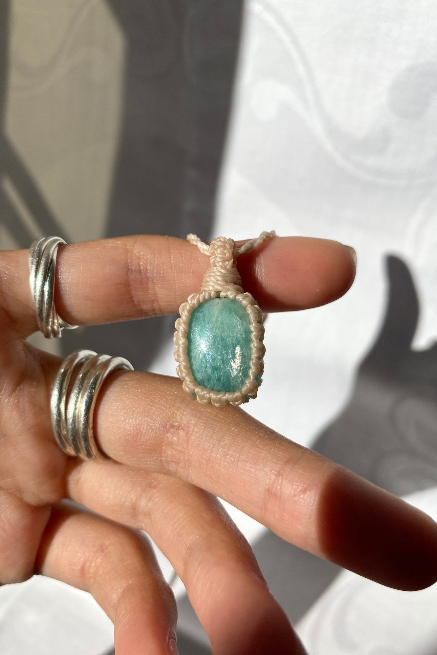 Hand holding a handmade Amazonite Macrame necklace from the Essence collection, featuring a high-quality blue gemstone in a delicate everyday-wear design.