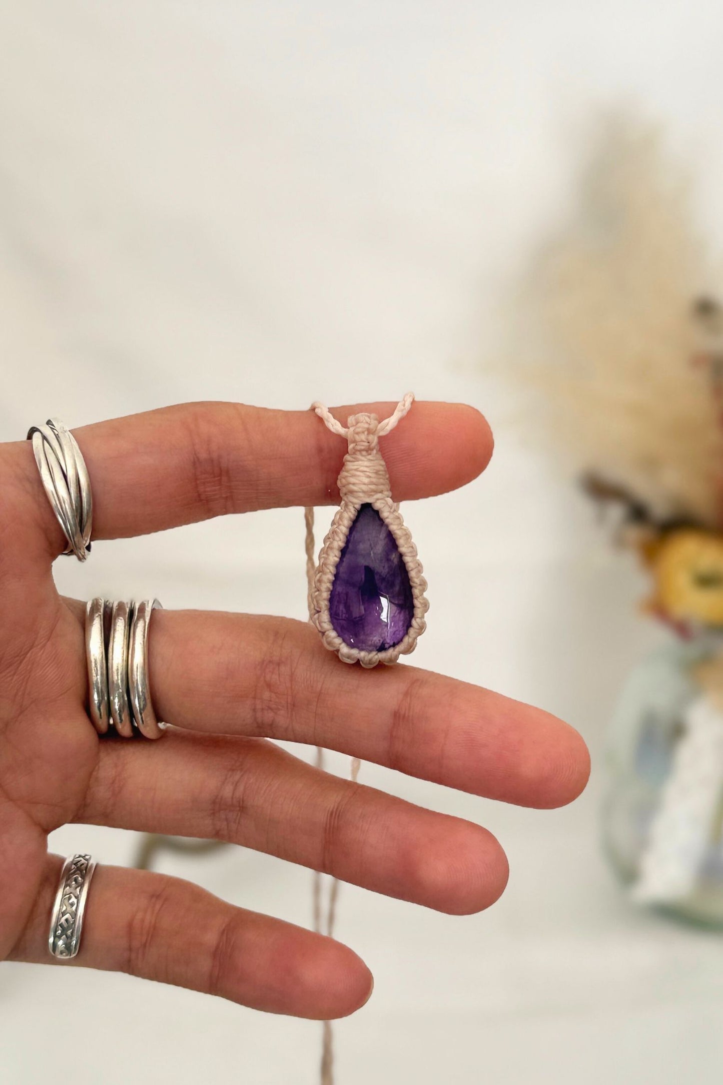 Hand holding a handmade Amethyst Macrame necklace from the Essence collection, featuring a high-quality gemstone in a delicate everyday-wear design.