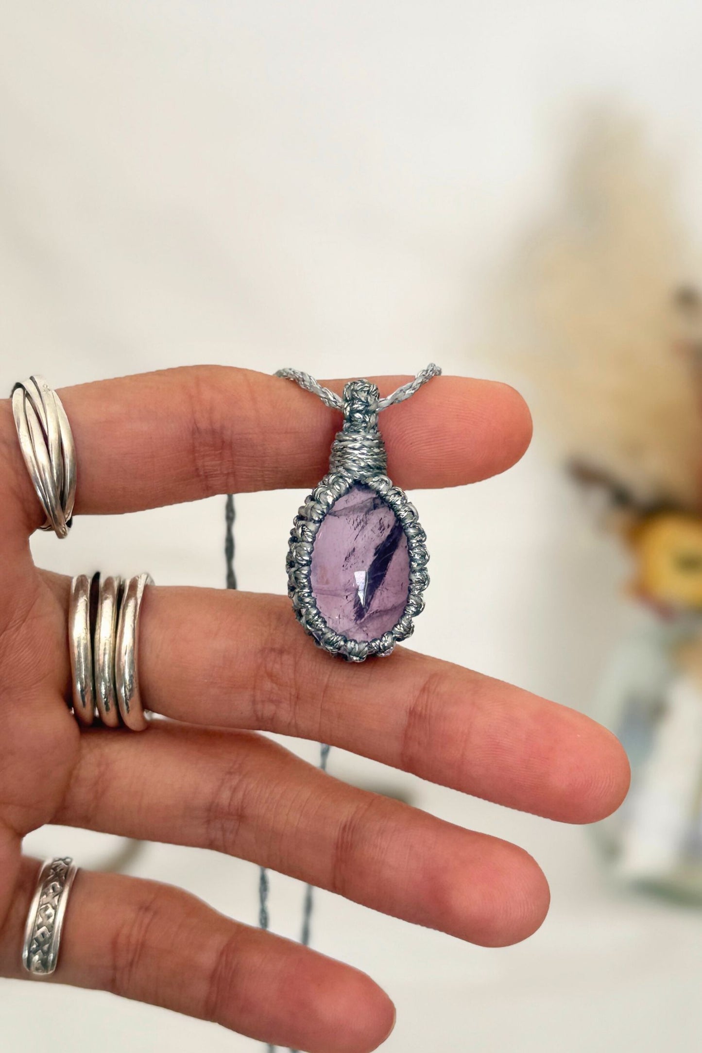 Hand holding a handmade Amethyst Macrame necklace from the Essence collection, featuring a high-quality gemstone in a delicate everyday-wear design.