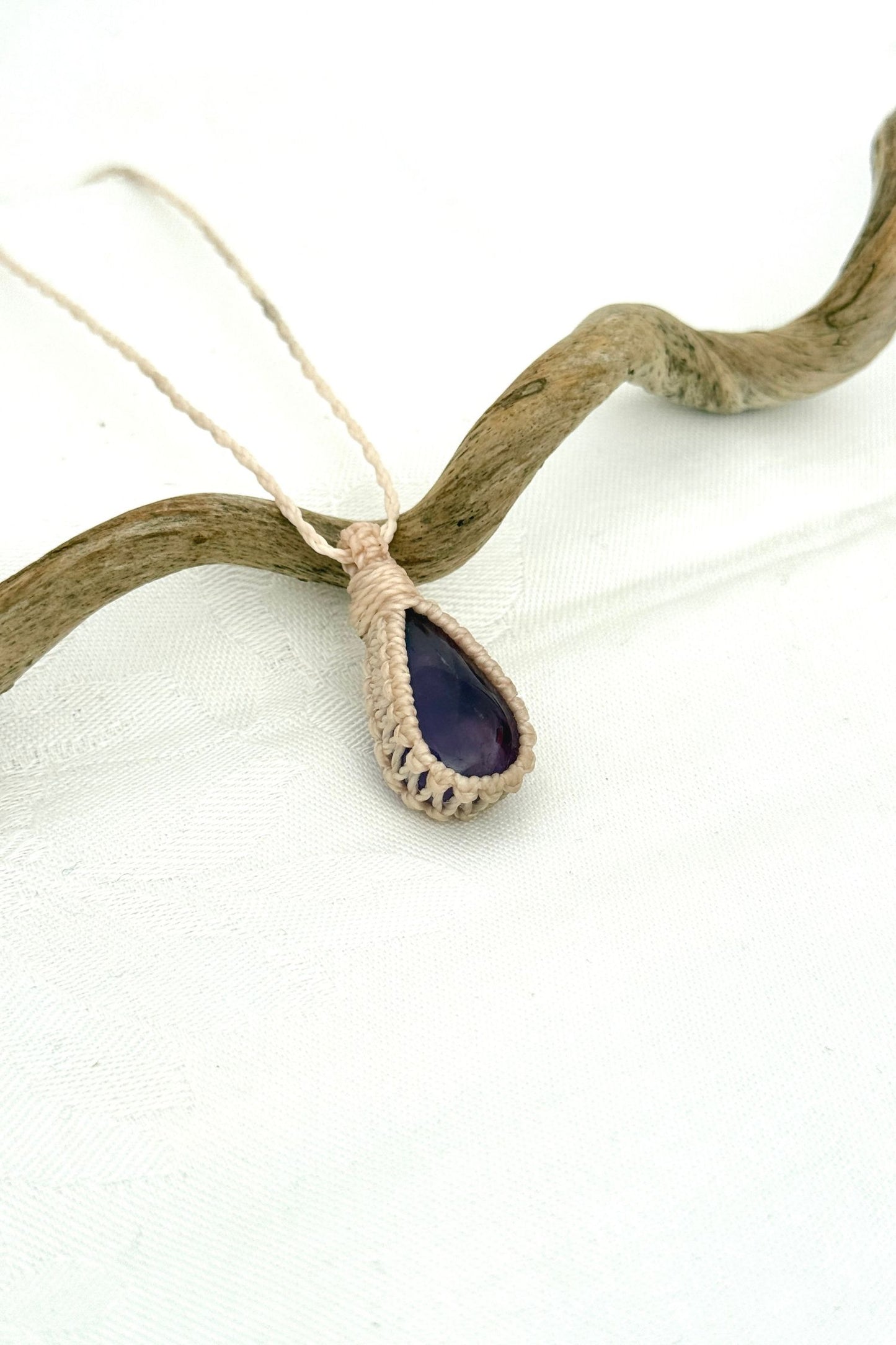Side angle view of the Amethyst Macrame necklace, showing the fine macrame details and the unique gemstone centerpiece.