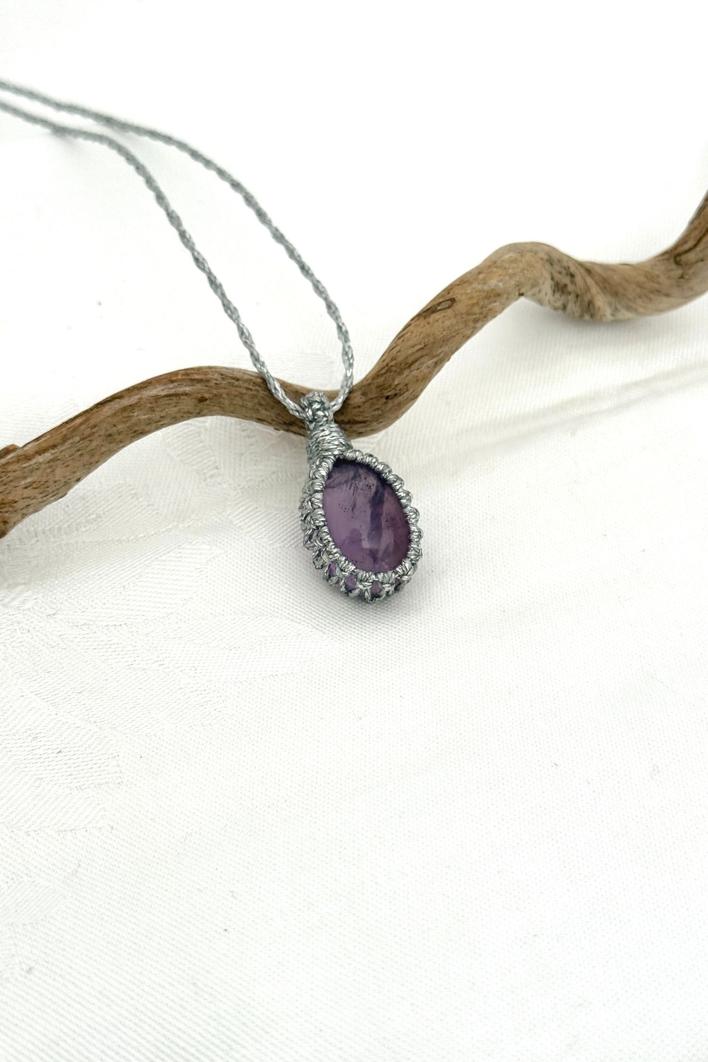 Side angle view of the Amethyst Macrame necklace, showing the fine macrame details and the unique gemstone centerpiece.