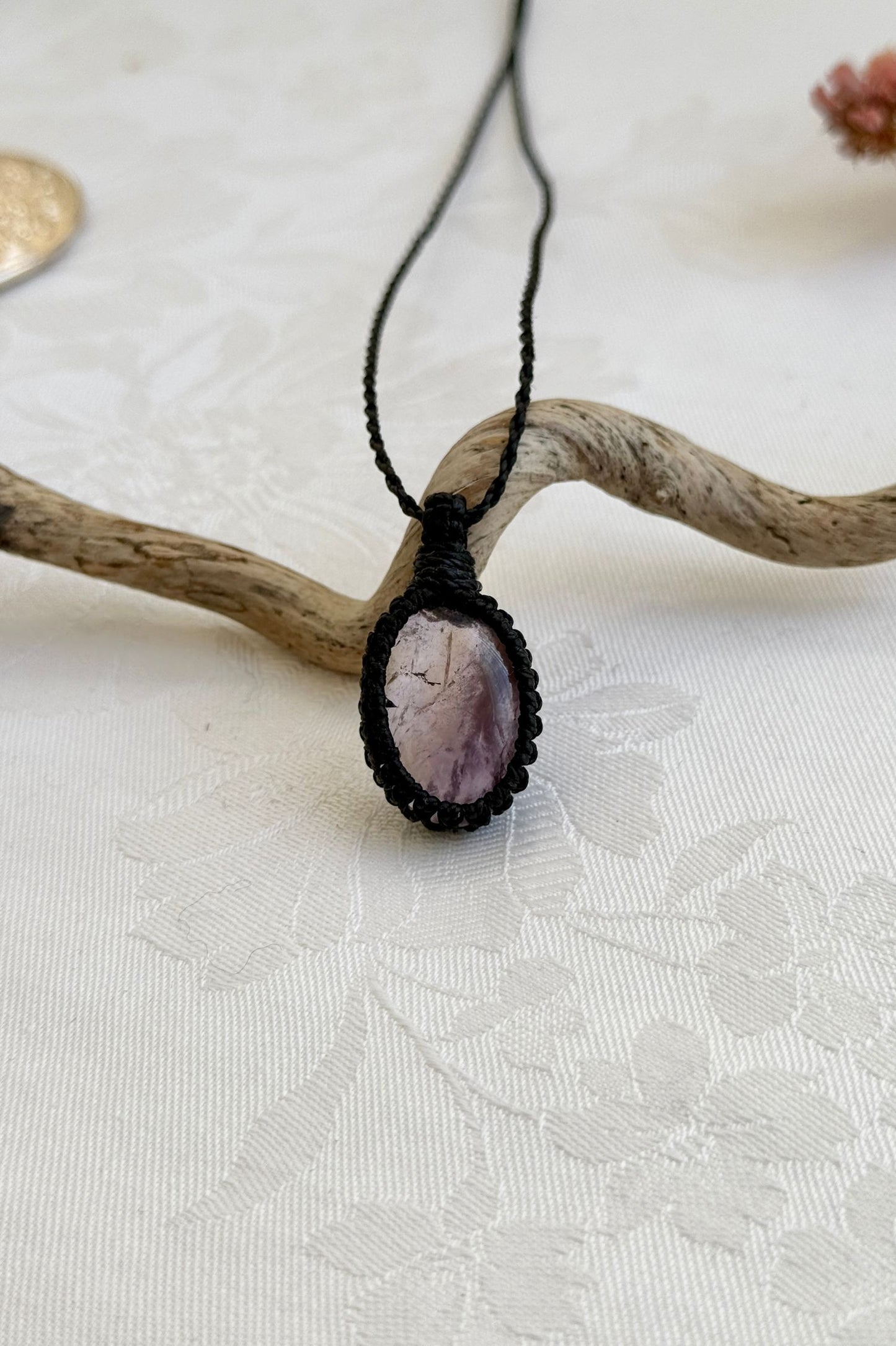 Handmade Ametrine macrame necklace with a black cord, laid flat to display its intricate design and natural gemstone.