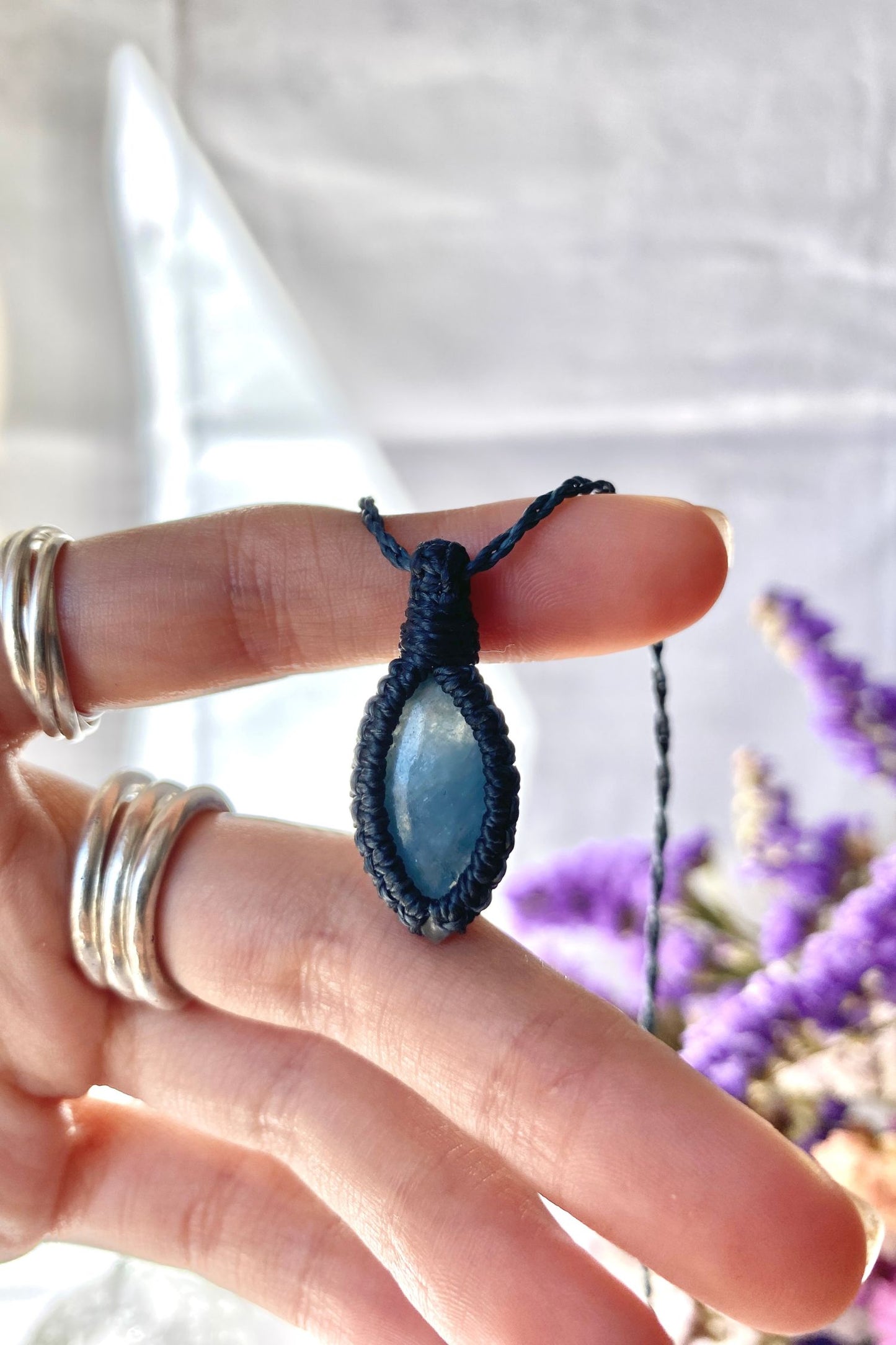 Close-up of handmade Aquamarine Macrame necklace in hand, showcasing the intricate macrame knotting and the vibrant blue hues of the gemstone.