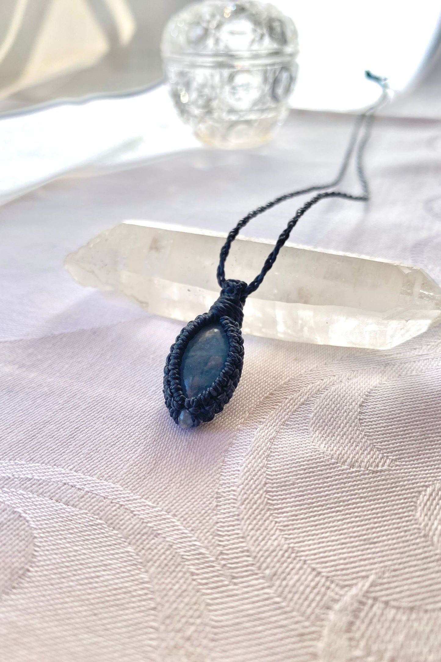 Side angle view of the Aquamarine Macrame necklace, showing the fine macrame details and the unique blue gemstone centerpiece.