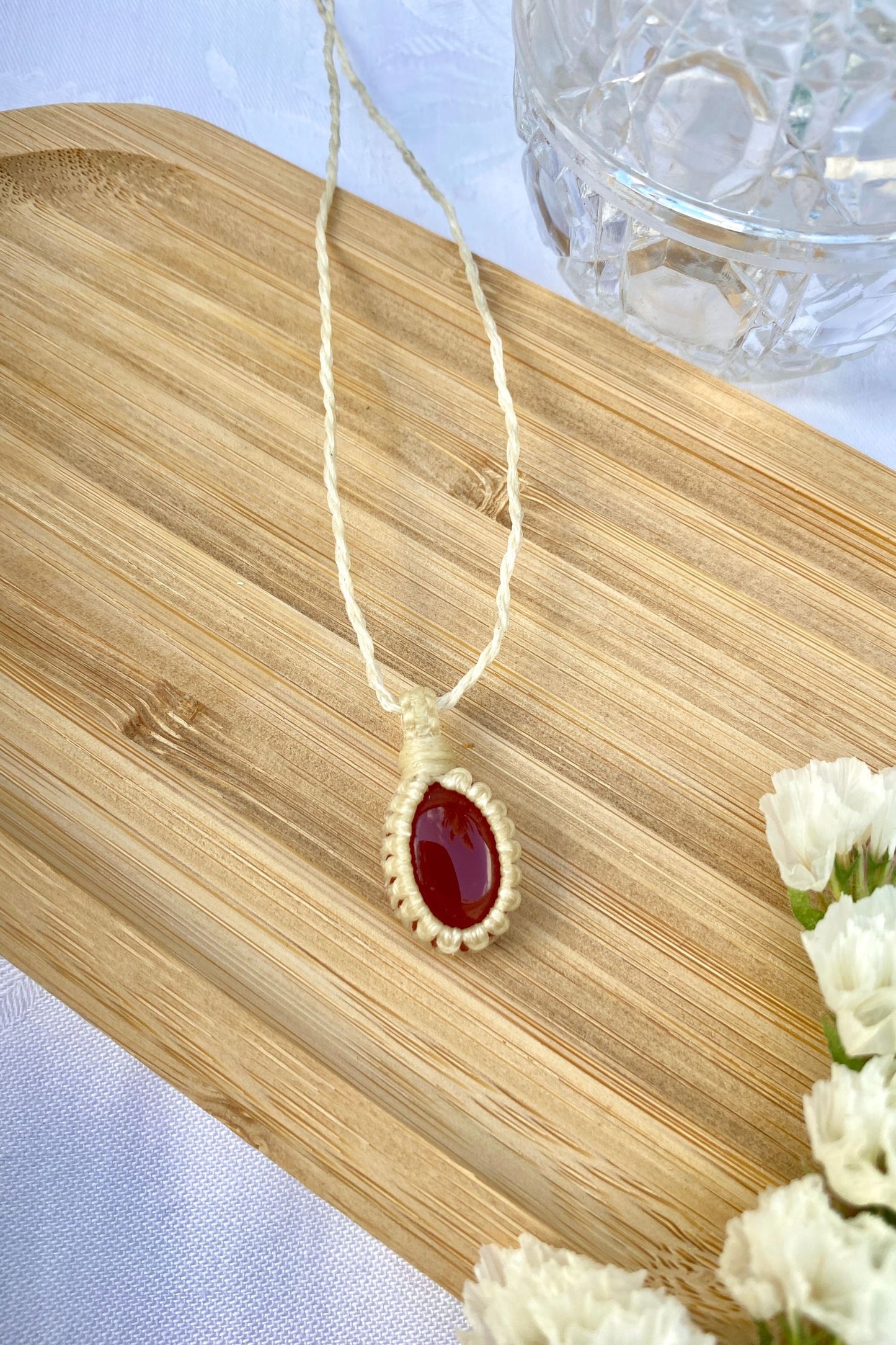 Handmade Carnelian macrame necklace displayed flat, highlighting its fiery red gemstone and warm, energizing tones.