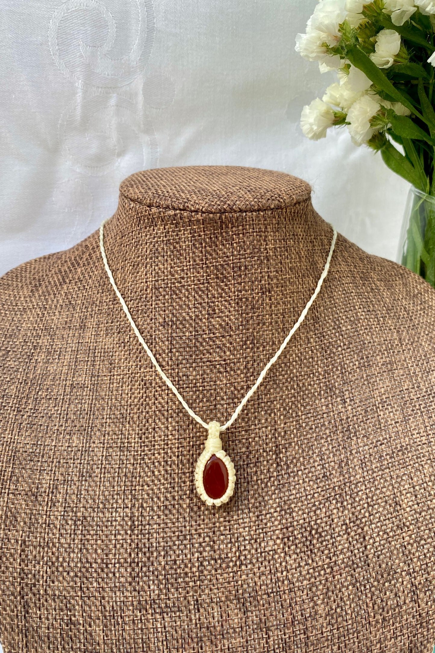 Handmade Carnelian macrame necklace showcased on a necklace stand, displaying its elegant minimalist design and vibrant gemstone.