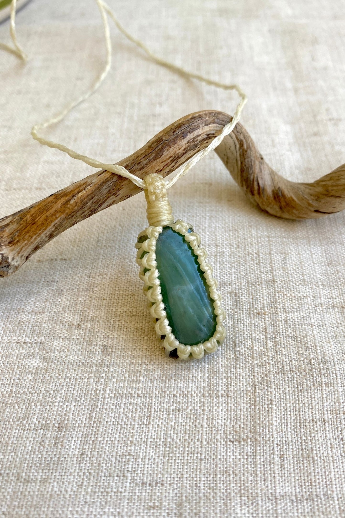 Side angle view of a handmade Chrysoprase macrame necklace, highlighting the gemstone’s deep green color and natural inclusions within the simple macrame design.