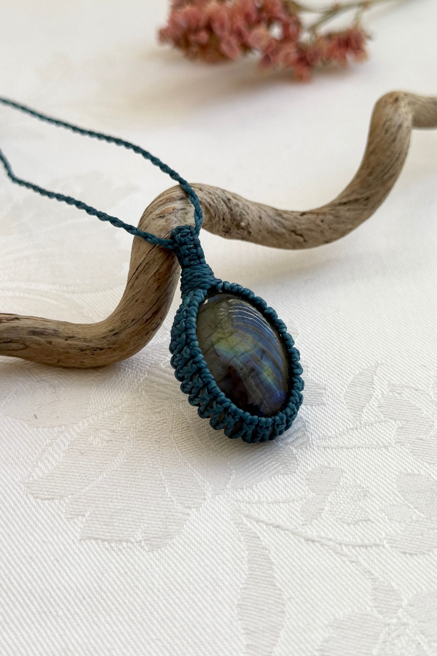 Side view of a Labradorite macrame necklace wrapped in blue cord, highlighting its elegant craftsmanship.