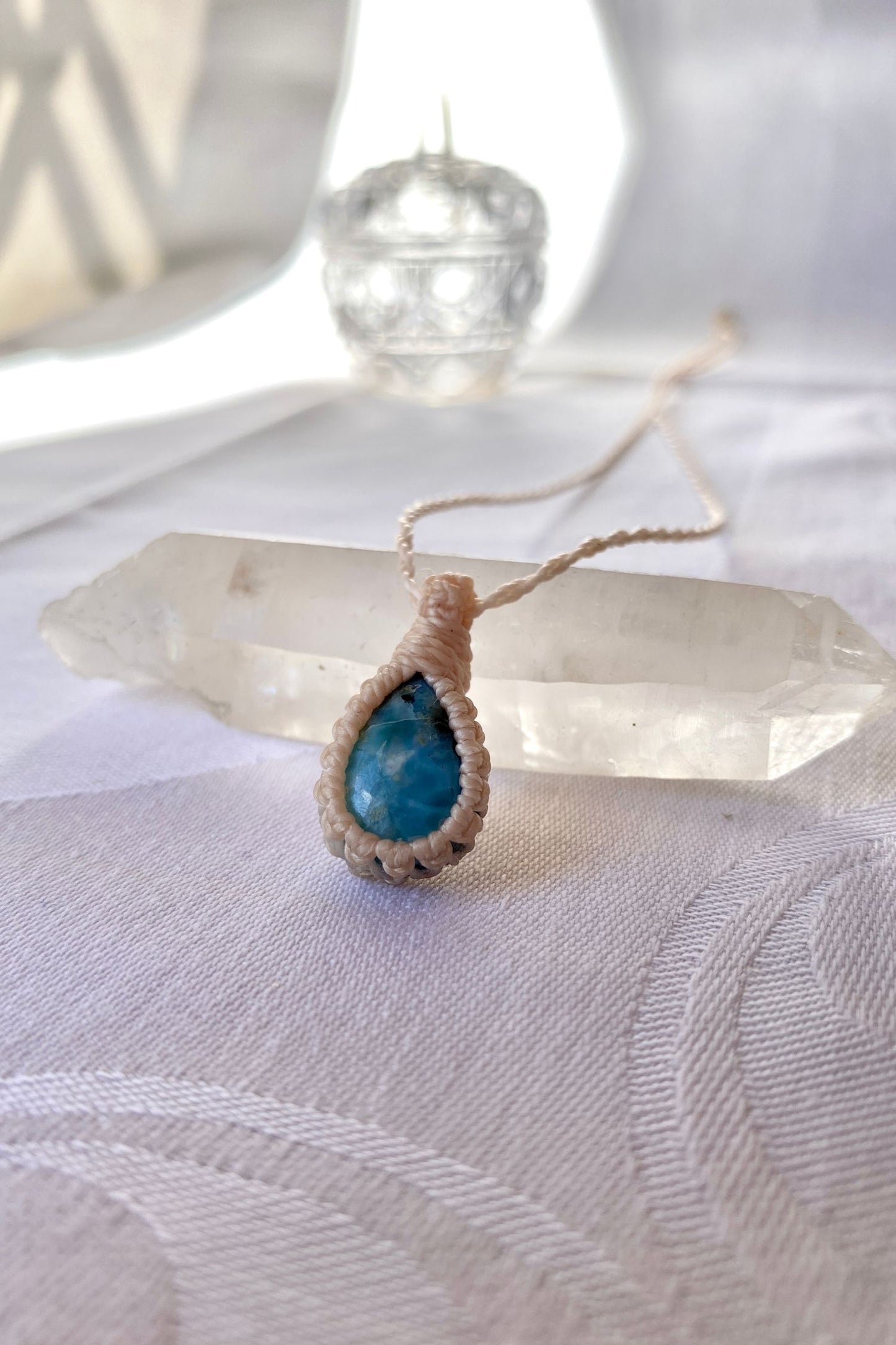 Side angle view of the Larimar Macrame necklace, showing the fine macrame details and the unique blue gemstone centerpiece.