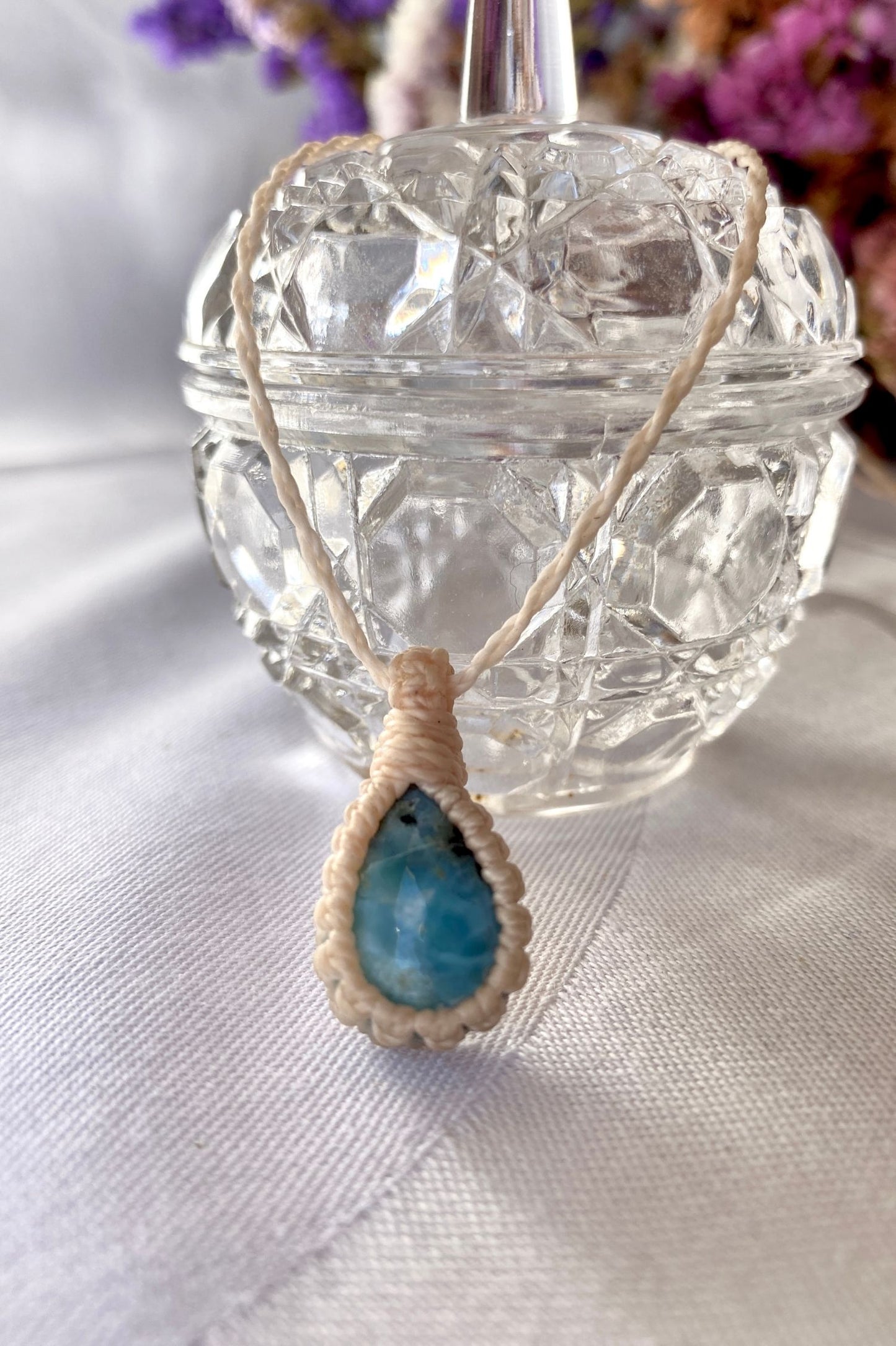 Handmade Larimar Macrame necklace displayed standing, highlighting the minimalist macrame design and the natural beauty of the blue gemstone.
