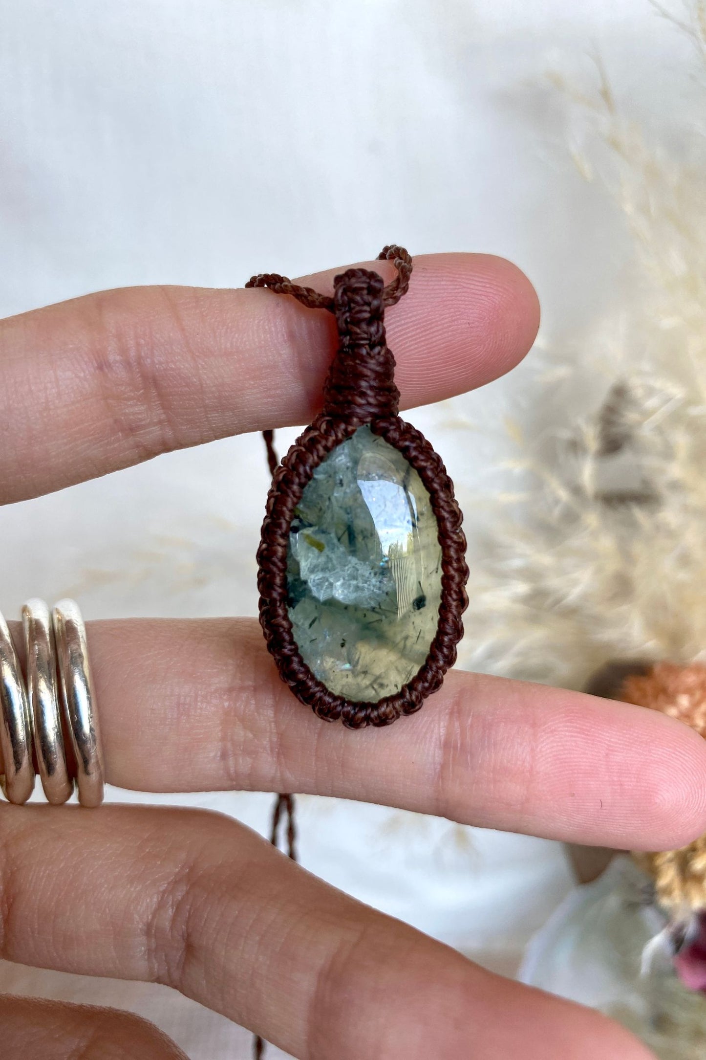 Close-up of a Prehnite gemstone in a macrame necklace, showing its delicate inclusions and soothing green color.