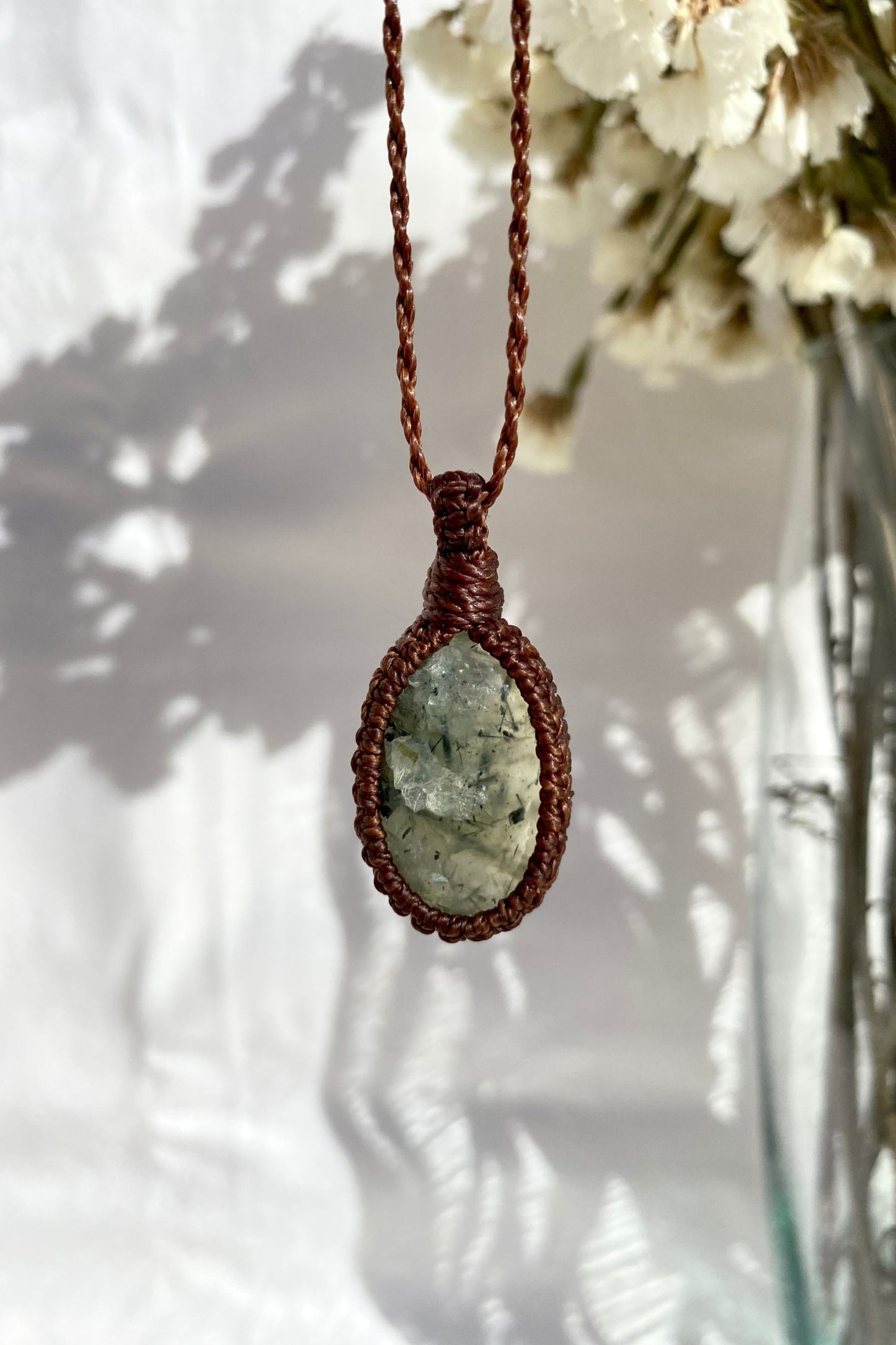 Handmade Prehnite macrame necklace displayed on a clean background, highlighting the gemstone’s soft green hue and intricate macrame design.