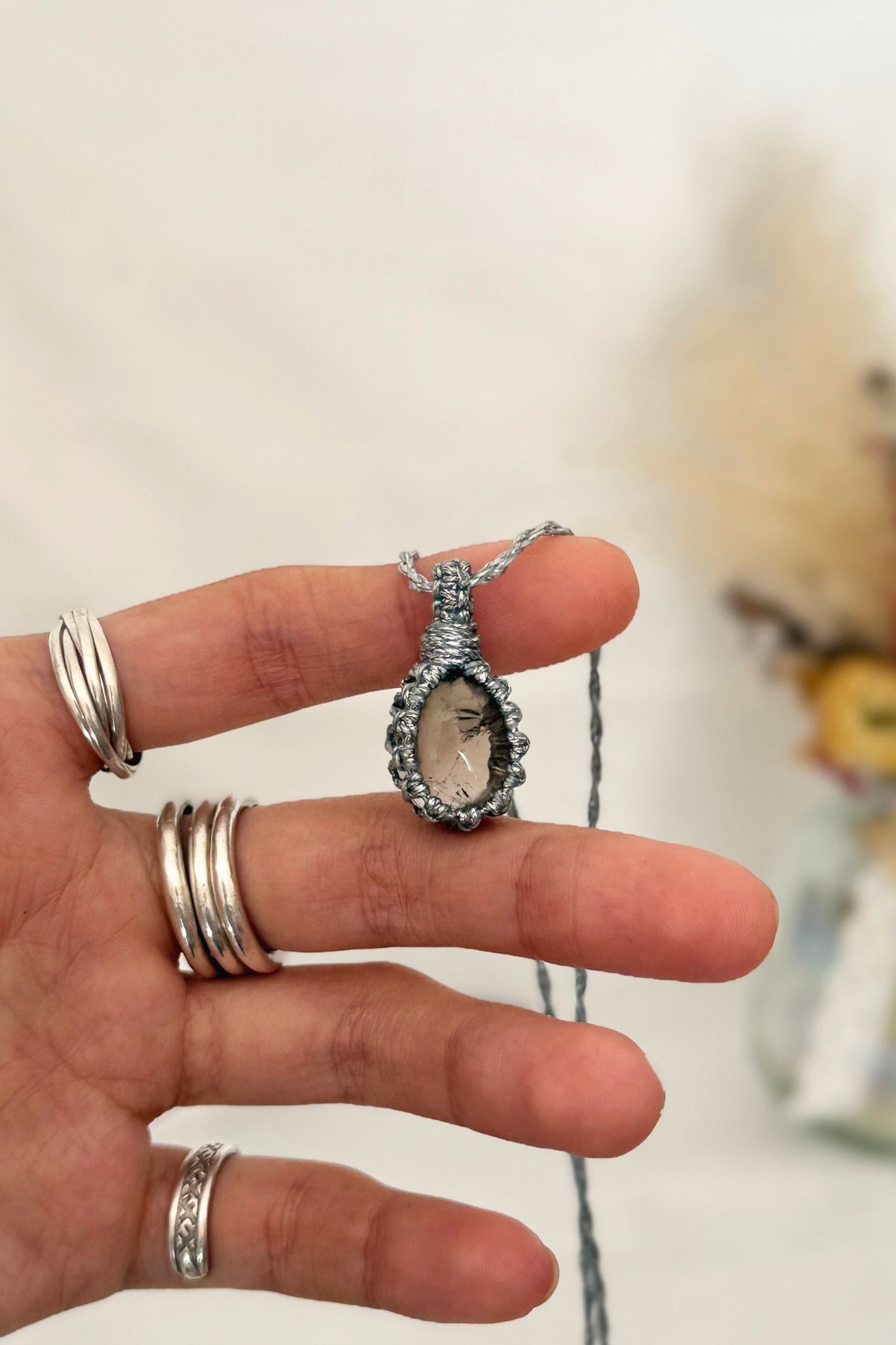 Hand holding a handmade Smoky Quartz Macrame necklace from the Essence collection, featuring a high-quality gemstone in a delicate everyday-wear design.