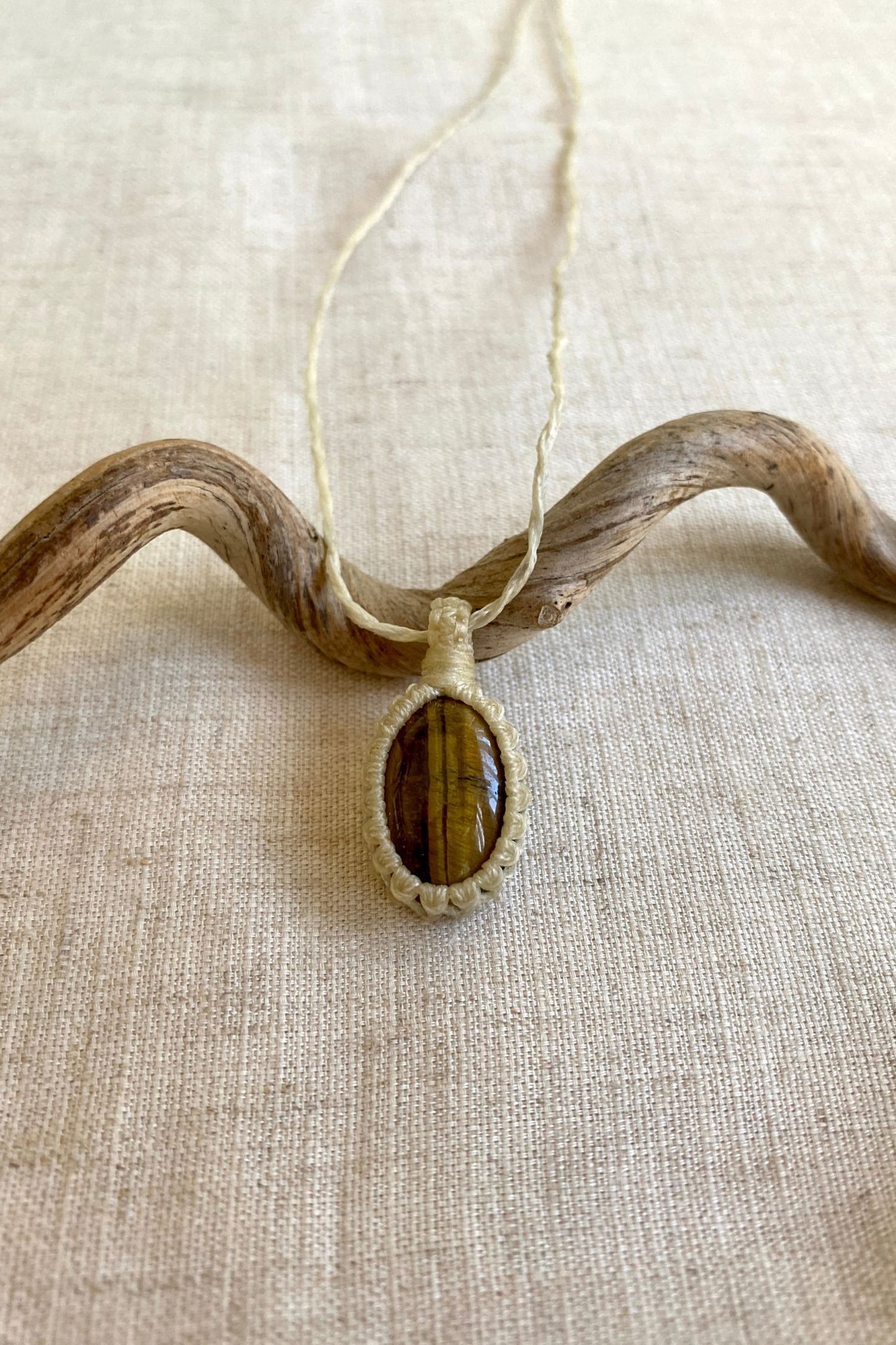 Handmade Tiger’s Eye macrame necklace laid flat, highlighting the gemstone’s striking golden-brown colors and natural patterns.