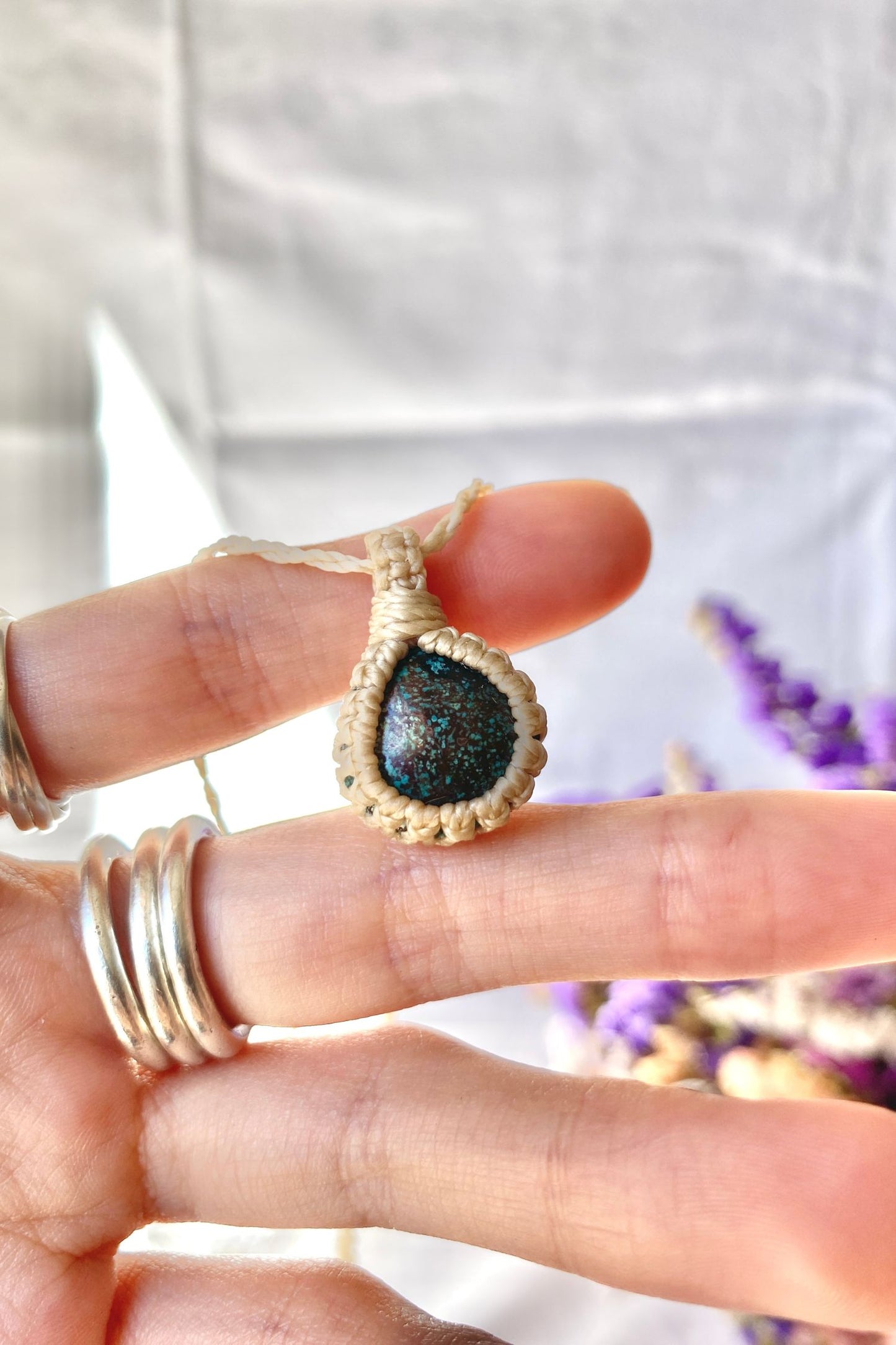 Close-up of handmade Turquoise Macrame necklace in hand, showcasing the intricate macrame knotting and the vibrant blue details of the gemstone.