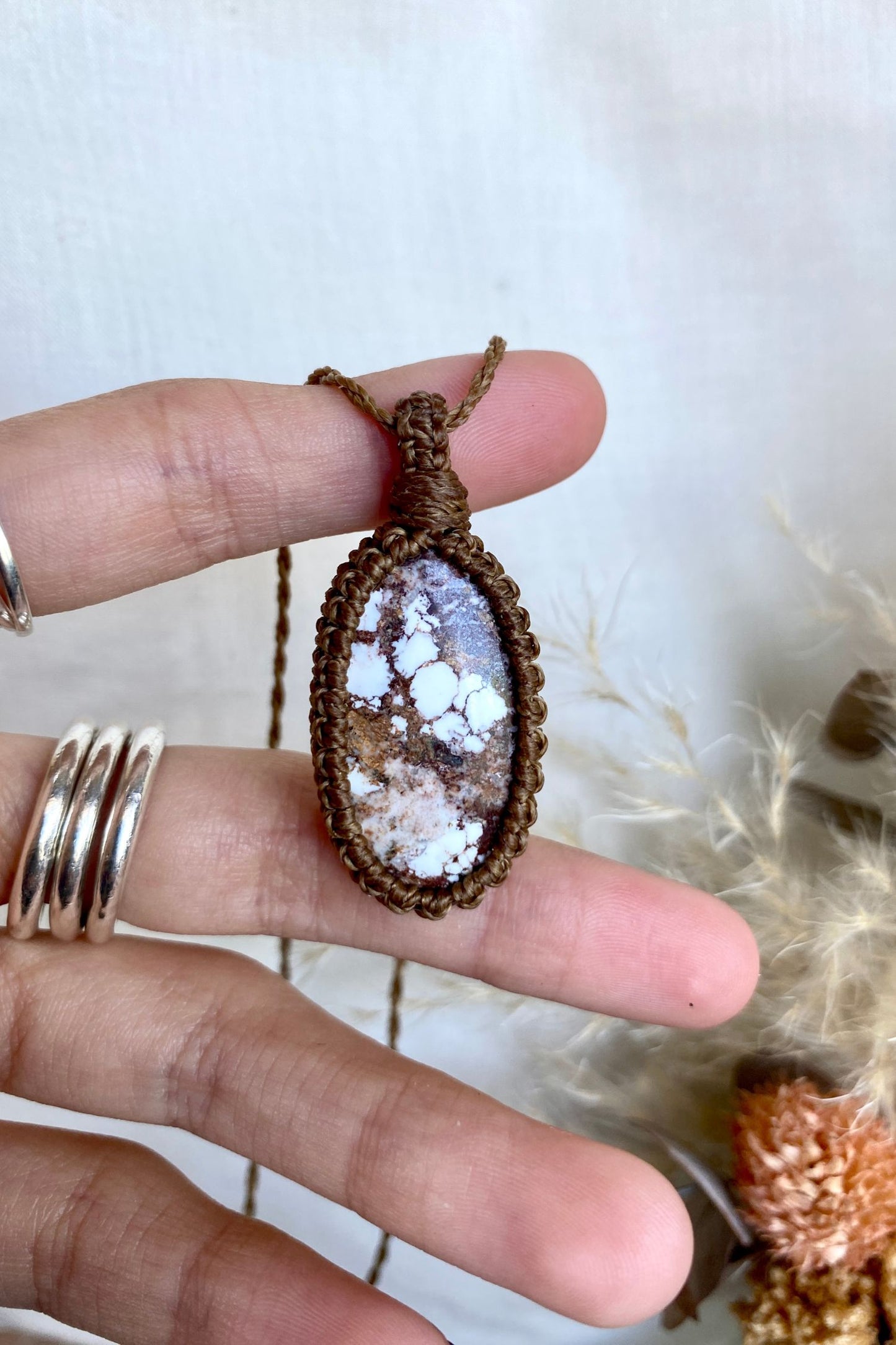 Close-up of a Wild Horse Magnesite gemstone in a macrame necklace, showcasing its distinctive marbled patterns in shades of brown, cream, and white.