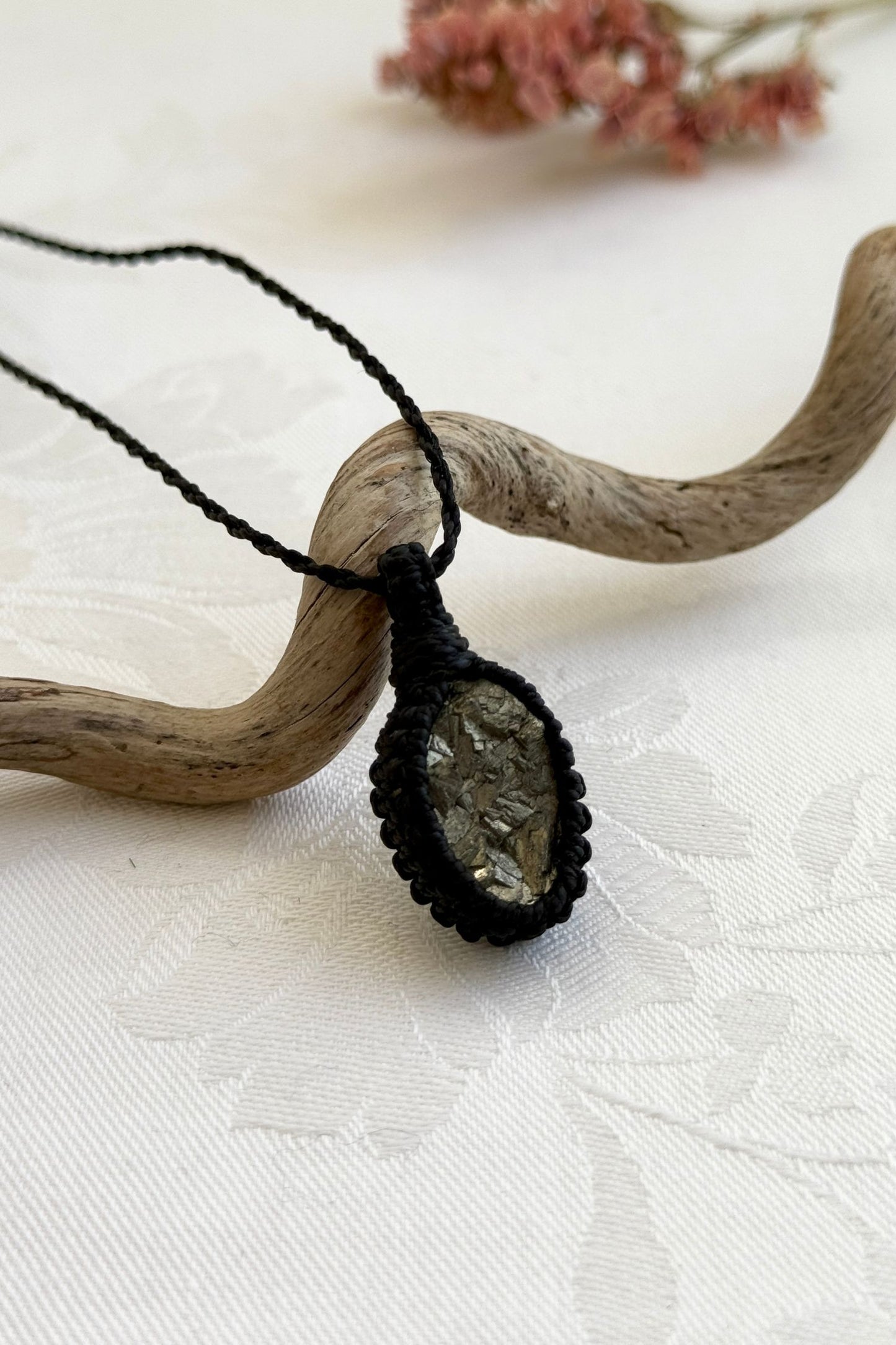 Side view of a Raw Pyrite macrame necklace wrapped in black cord, highlighting its elegant craftsmanship.