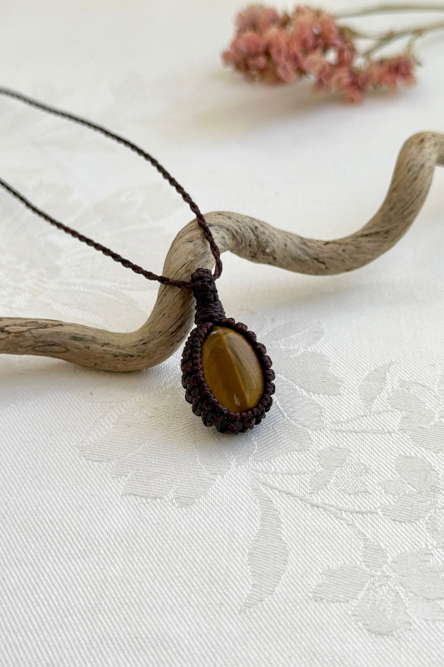 Side view of a Tiger’s Eye macrame necklace wrapped in brown cord, highlighting its elegant craftsmanship.