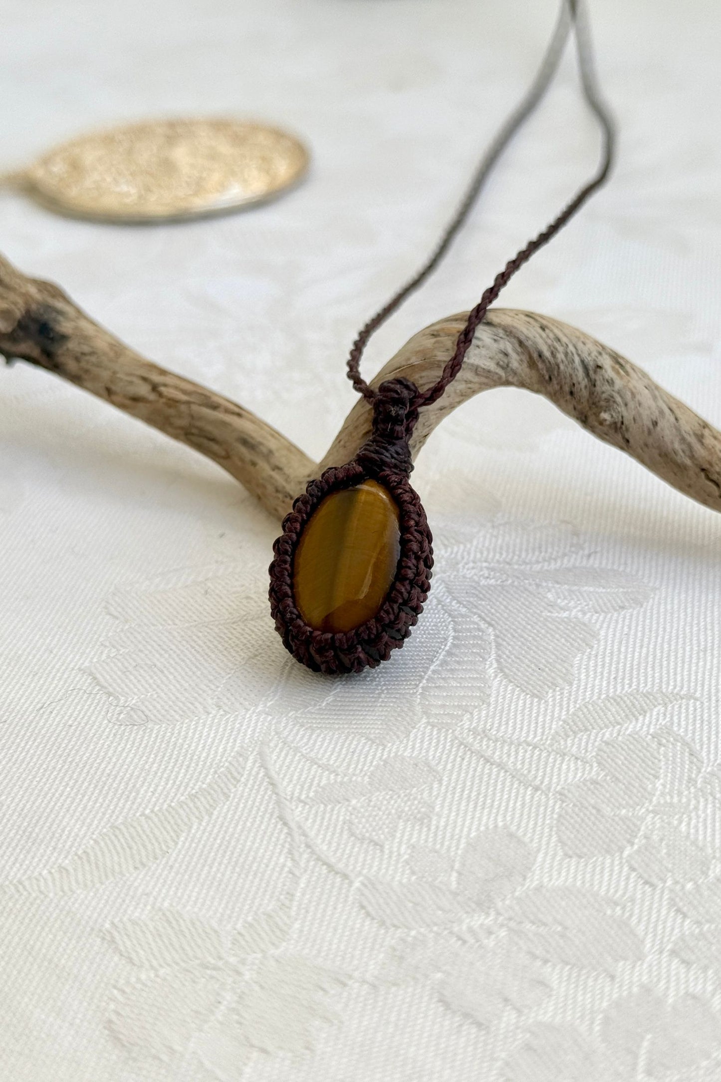 Alternate side view of a handmade Tiger’s Eye macrame necklace, focusing on the gemstone’s natural glow.