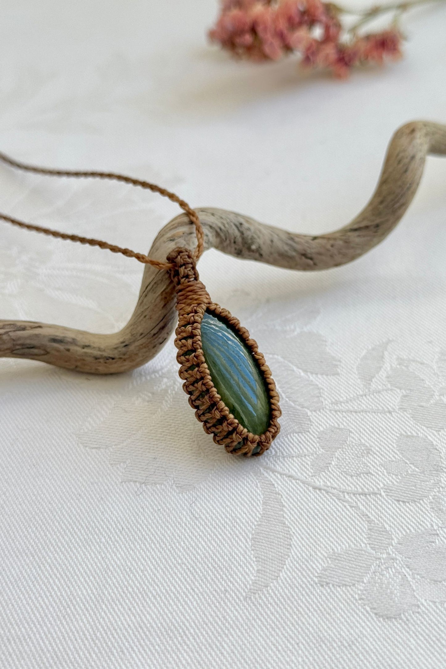 Side view of a Vesuvianite macrame necklace wrapped in golden brown cord, highlighting its elegant craftsmanship.