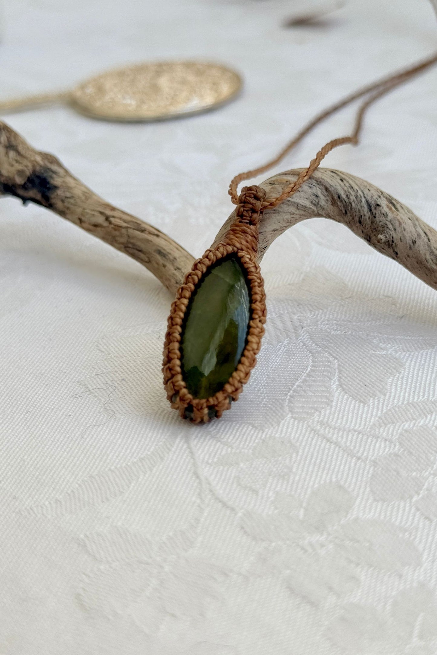Alternate side view of a handmade Vesuvianite macrame necklace, focusing on the gemstone’s natural glow.