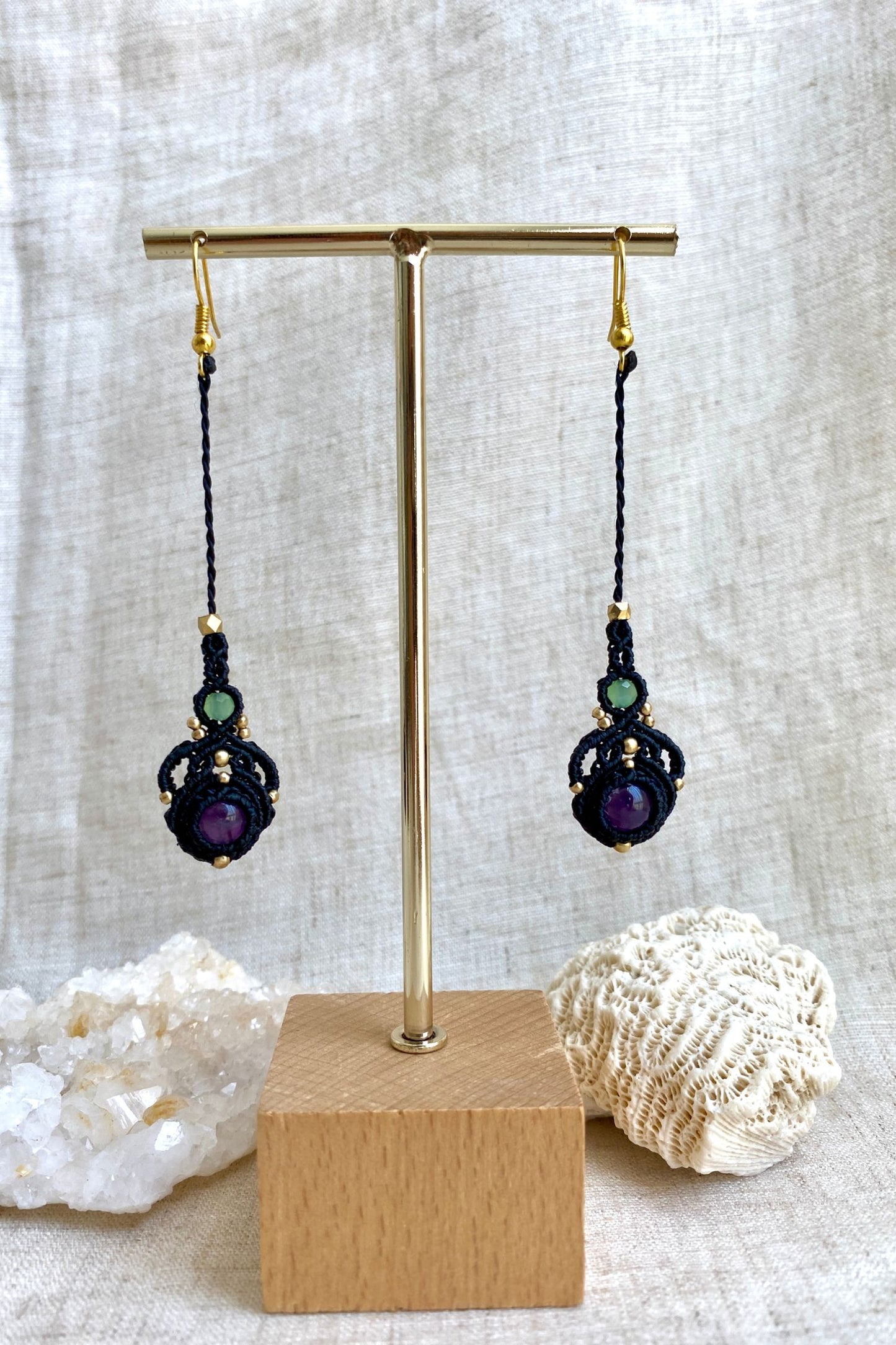 Handmade macrame earrings with amethyst and prehnite gemstones displayed on an earring stand, emphasizing the elegant long drop design and gemstone contrast.