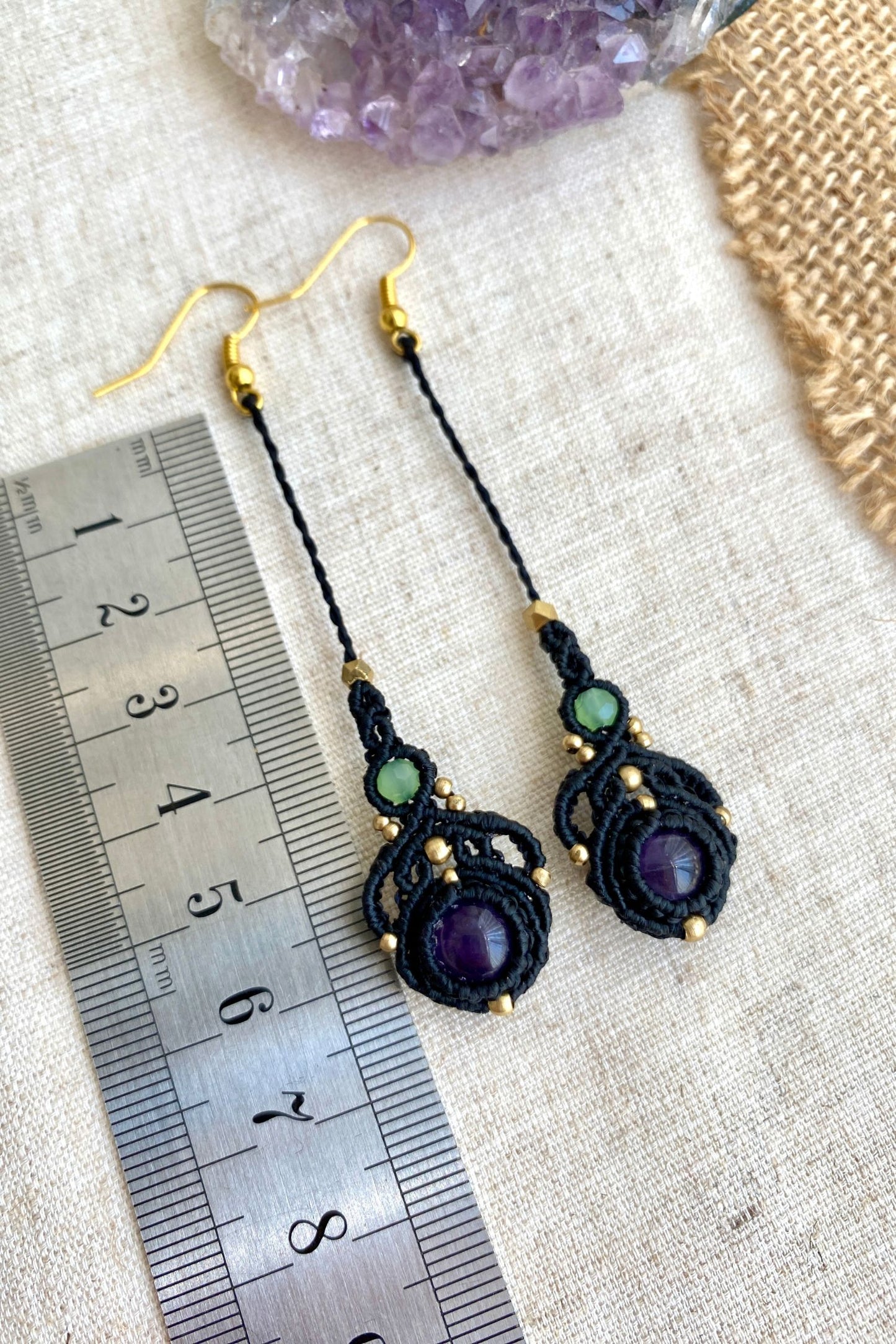 Handmade macrame earrings with amethyst and prehnite gemstones, laid flat alongside a ruler to show the length and size of the earrings.