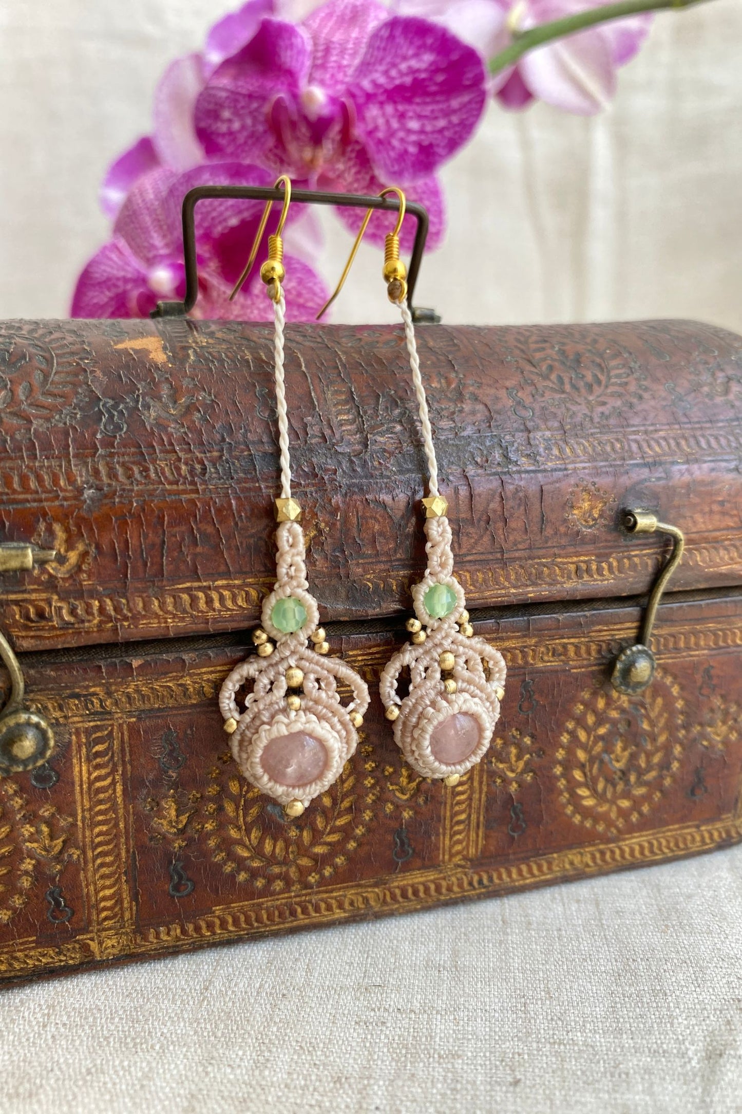 Artistic shot of handmade macrame earrings with rose quartz and prehnite gemstones, showcasing the elegant design and lightweight nature of the earrings.