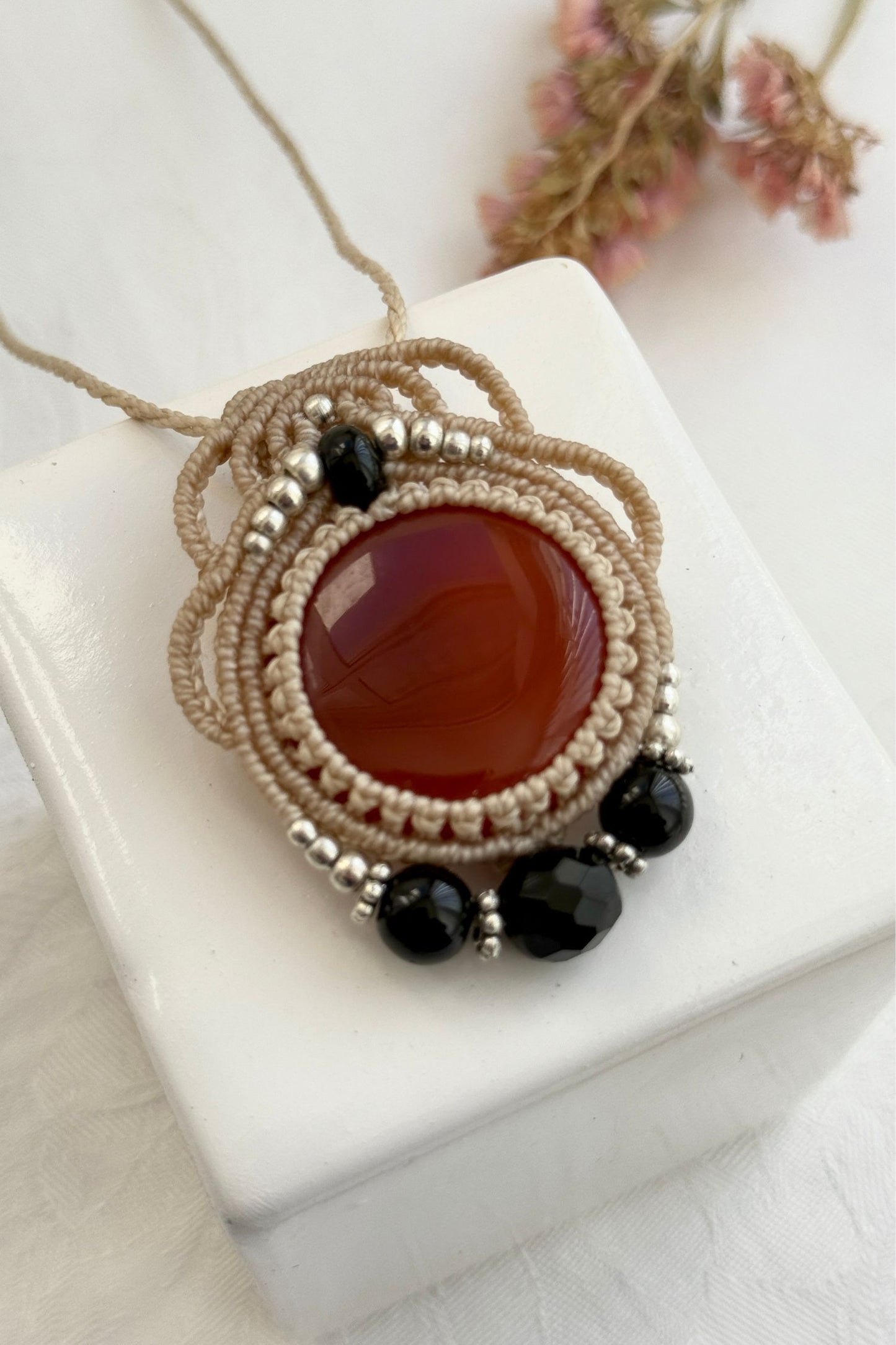 Detailed close-up of Carnelian and Onyx gemstones in a handmade macrame necklace. Showcasing natural textures and gemstone glow.