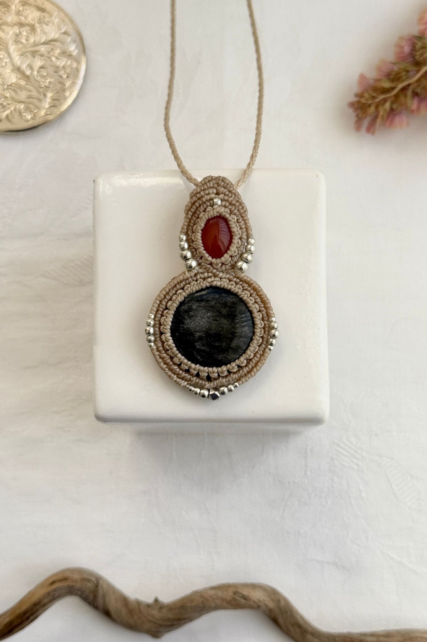 Handmade macrame necklace with Carnelian and Silver Sheen Obsidian gemstones, part of the Nocturnal Collection. One-of-a-kind design, laid flat for an artistic display.