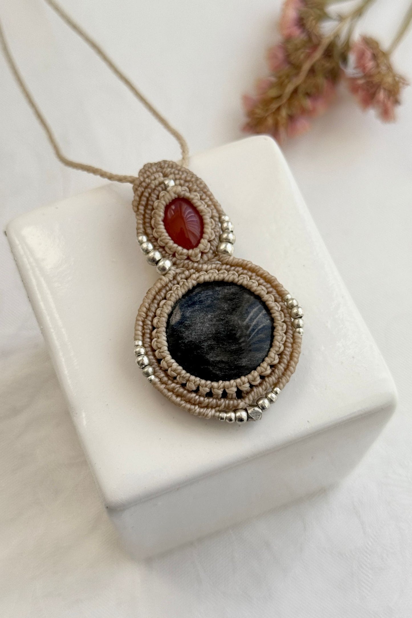 Detailed close-up of Carnelian and Silver Sheen Obsidian gemstones in a handmade macrame necklace. Showcasing natural textures and gemstone glow.