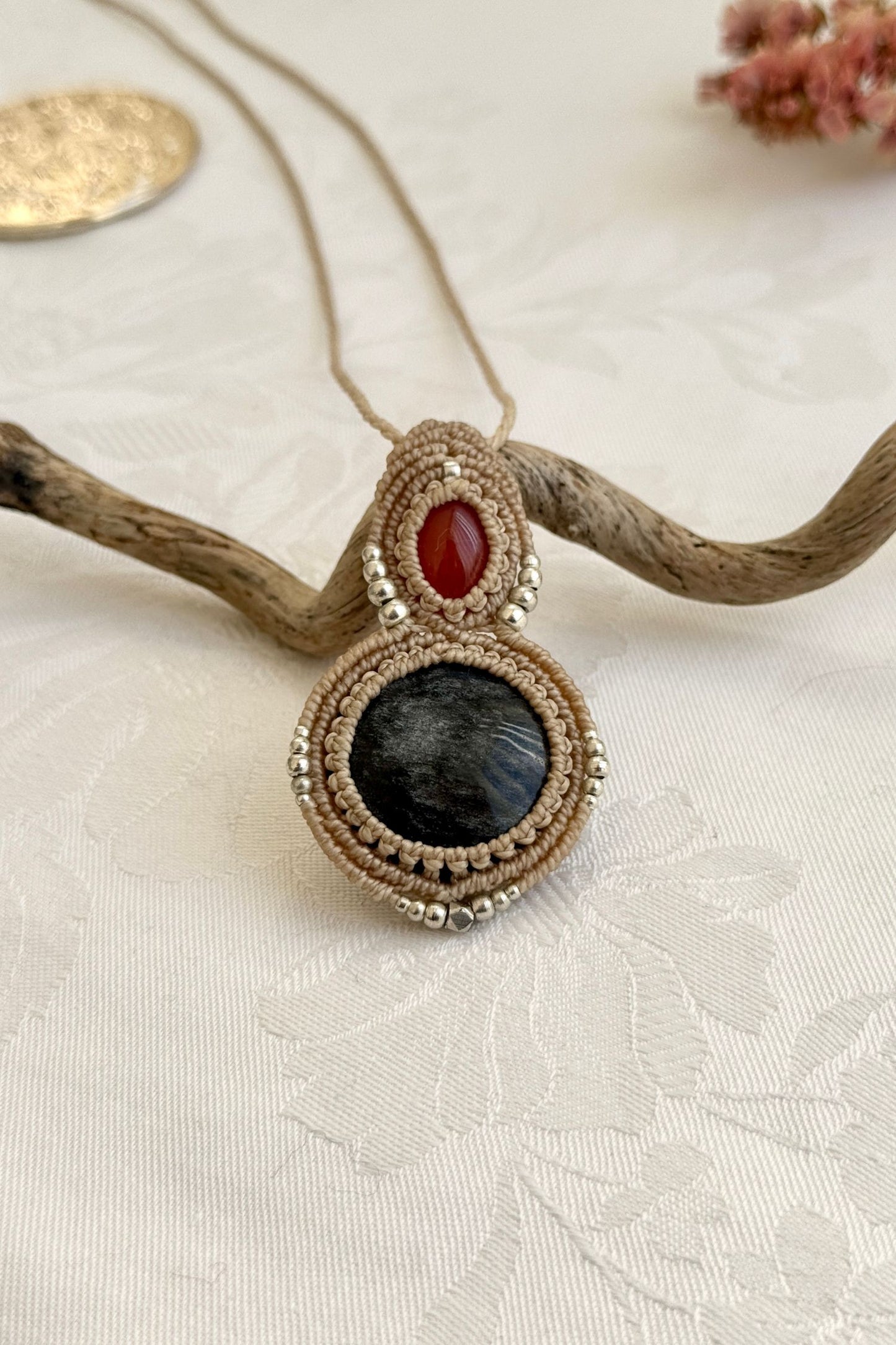 Close-up of the Carnelian and Silver Sheen Obsidian macrame necklace in a unique setting. Highlighting the craftsmanship and gemstone details.