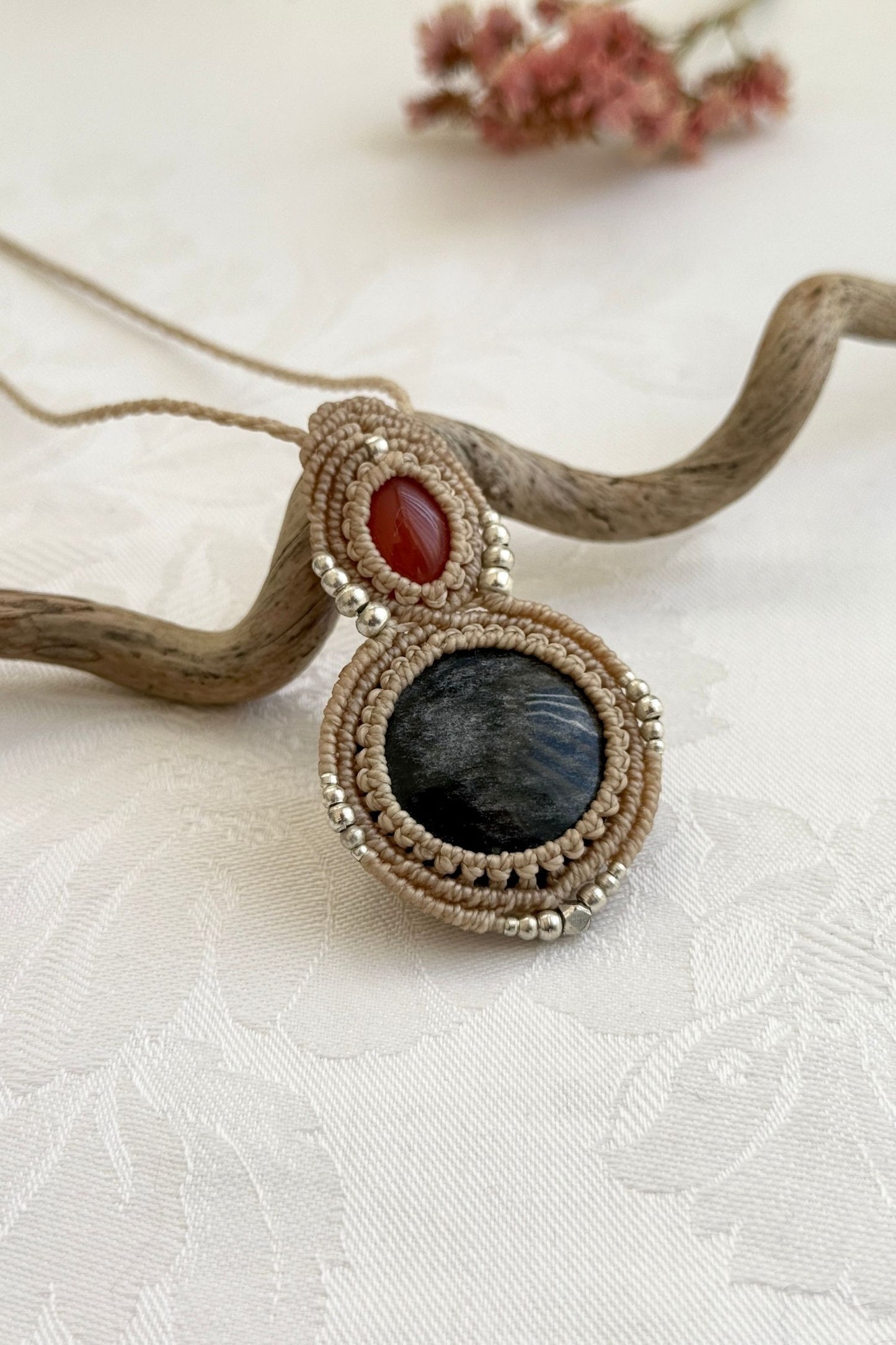 Side-angle view of the handmade macrame necklace with Carnelian and Silver Sheen Obsidian. Showcasing depth, knotting details, and stone textures.