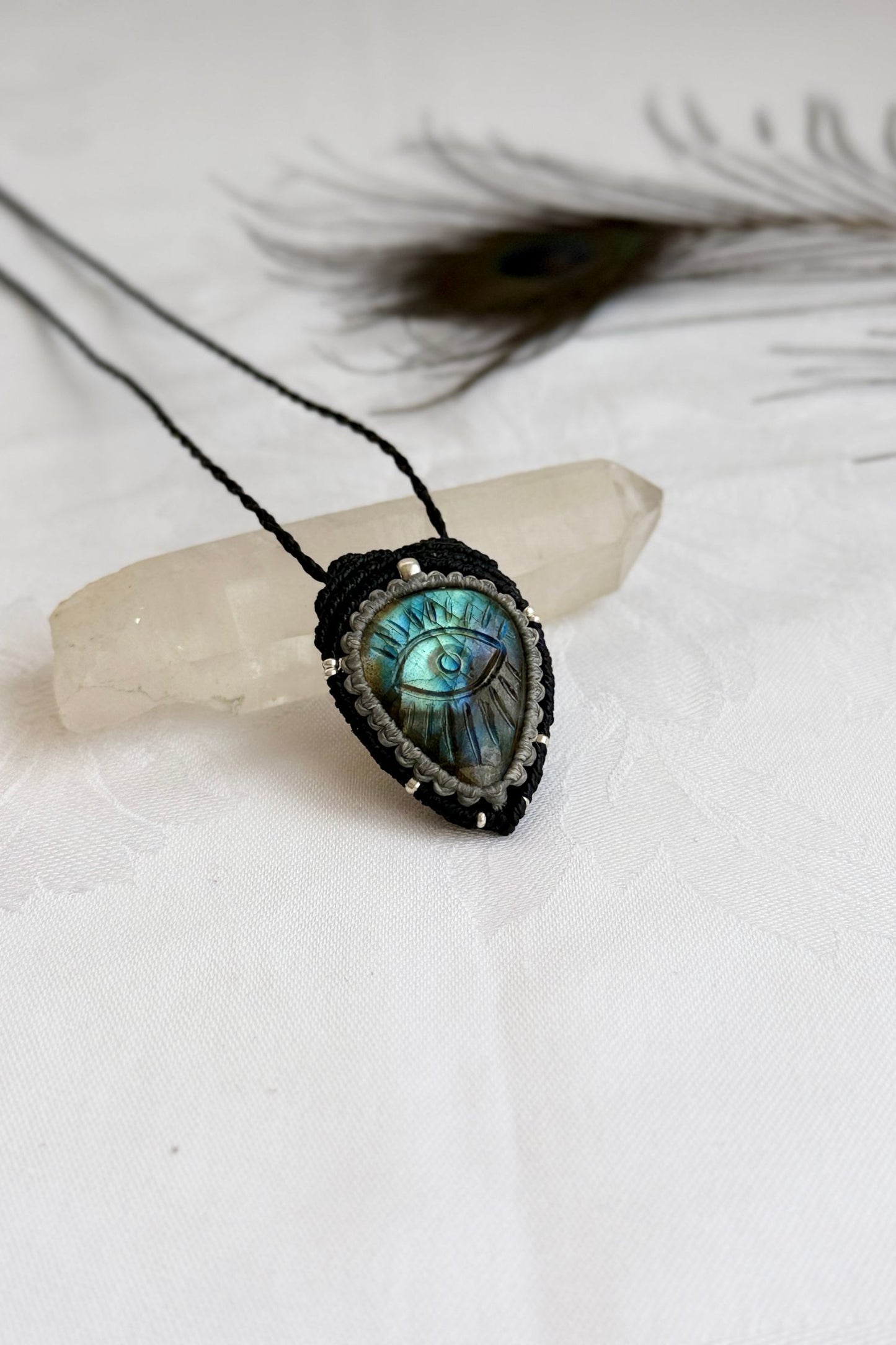 Handmade Labradorite macrame necklace with carved protective eye design, laid flat to show gemstone details and craftsmanship.